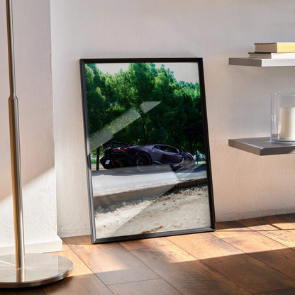 Lamborghini Revuelto poster featuring black sports car against green trees, modern wall art in black frame.