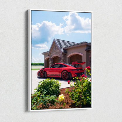 Vertical canvas art featuring a red Porsche 911 GT3 RS parked by a house under a blue sky with clouds.