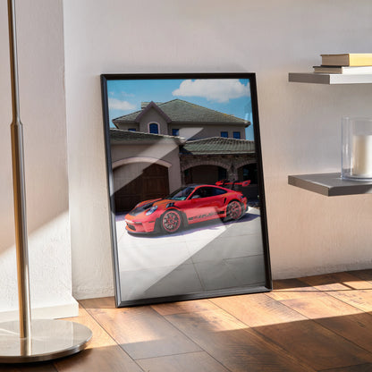 Porsche 911 GT3 RS red sports car poster framed as wall art leaning against sunlit wall.