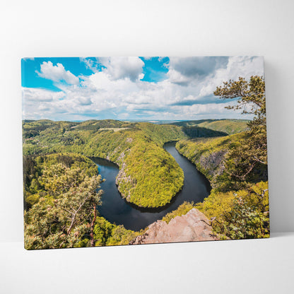 Canvas print of meandering river through lush green forest valleys under blue sky