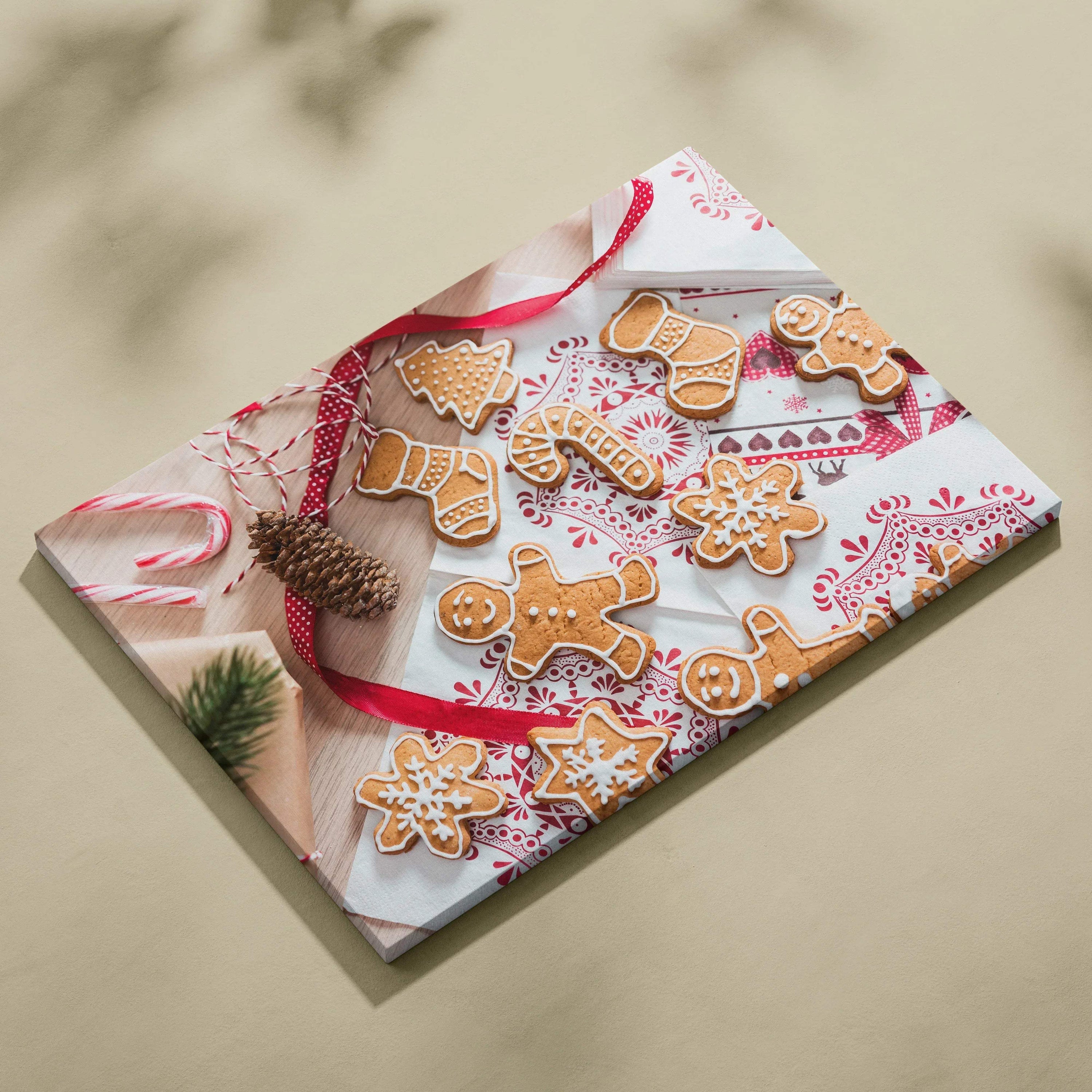 Canvas wall art featuring festive gingerbread cookies with white icing on a red and white patterned cloth background.