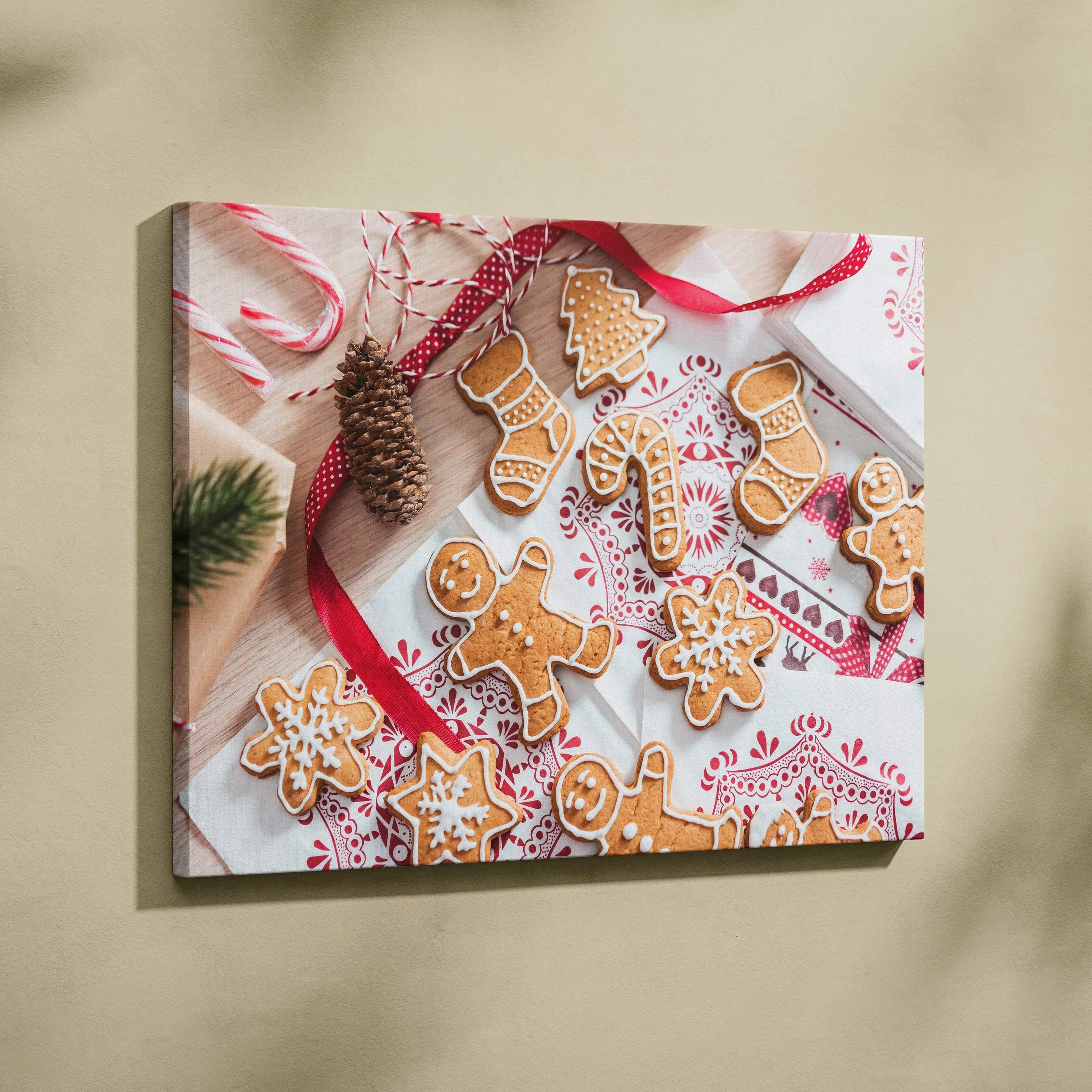 Canvas wall art featuring festive gingerbread cookies with red ribbon and pinecone on a patterned white cloth.