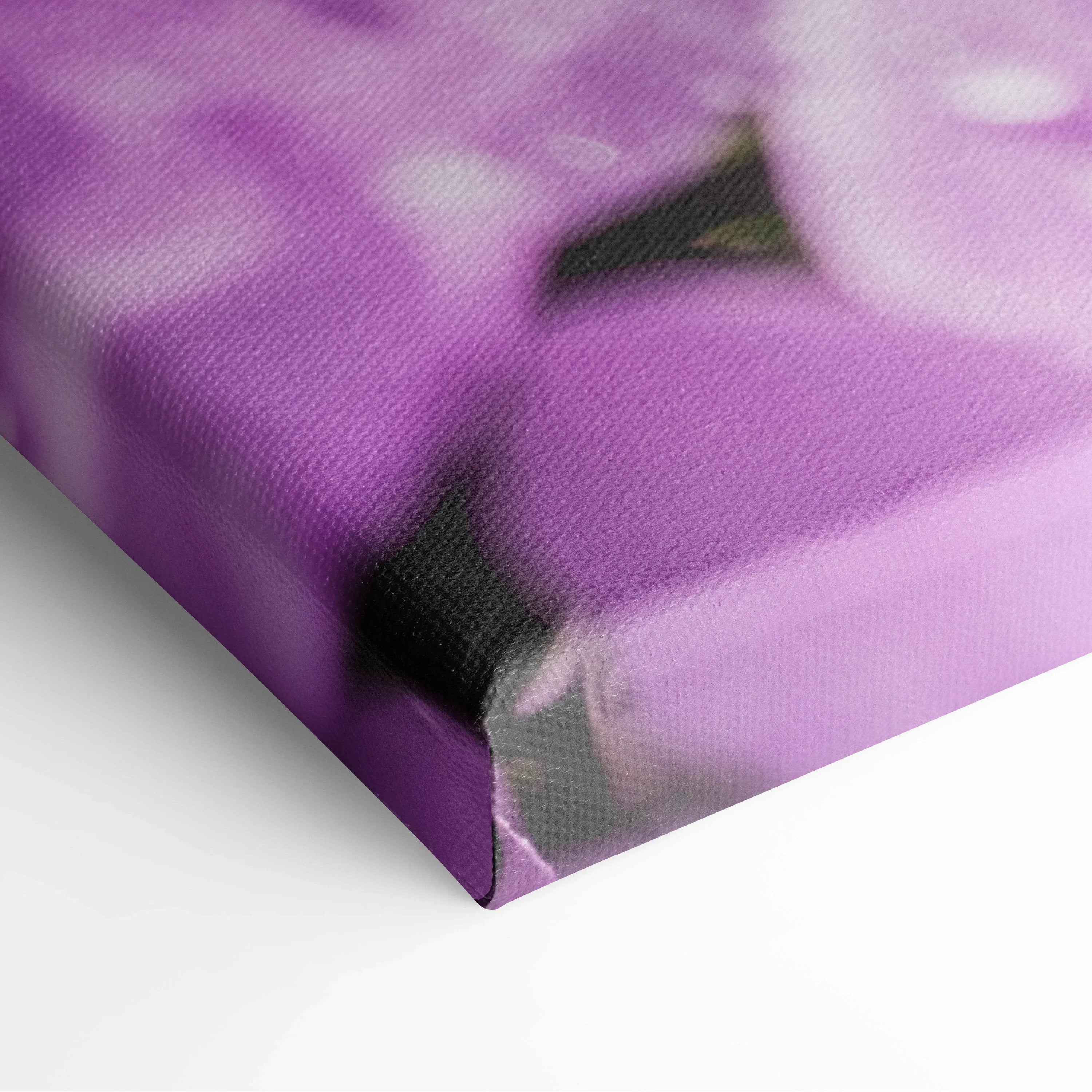 Close-up of purple floral canvas wall art showing textured fabric and blooming flower details on wrapped edges.