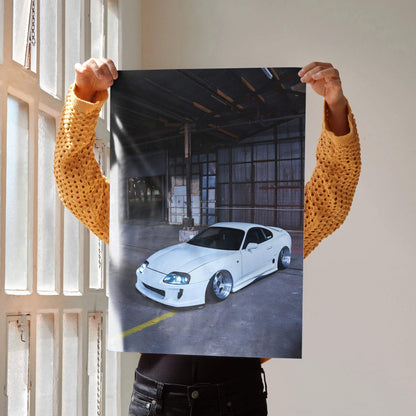 Toyota Supra MK4 white sports car poster held indoors, automotive wall art with warehouse background.