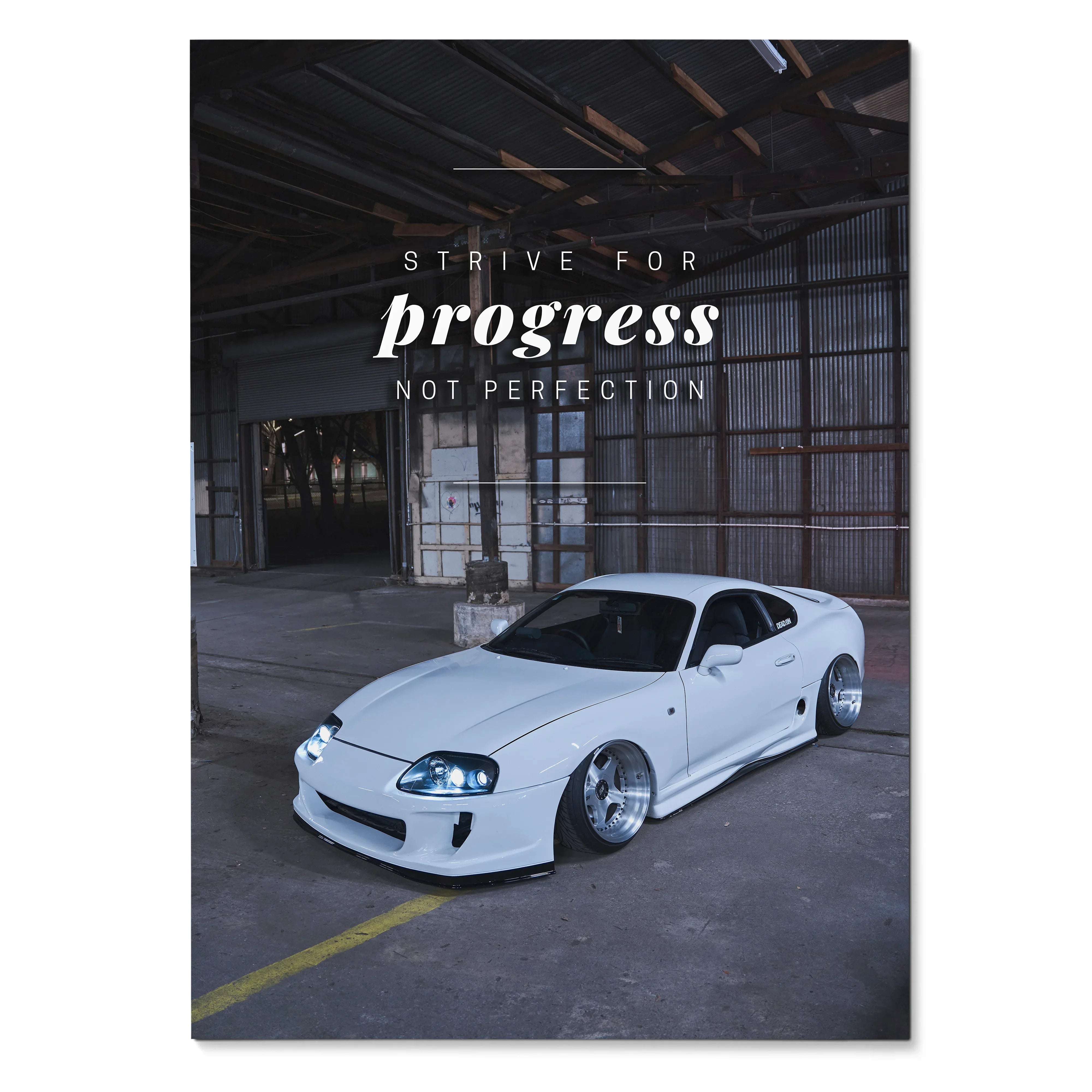 White Toyota Supra Mk4 in industrial garage with motivational quote poster wall art.