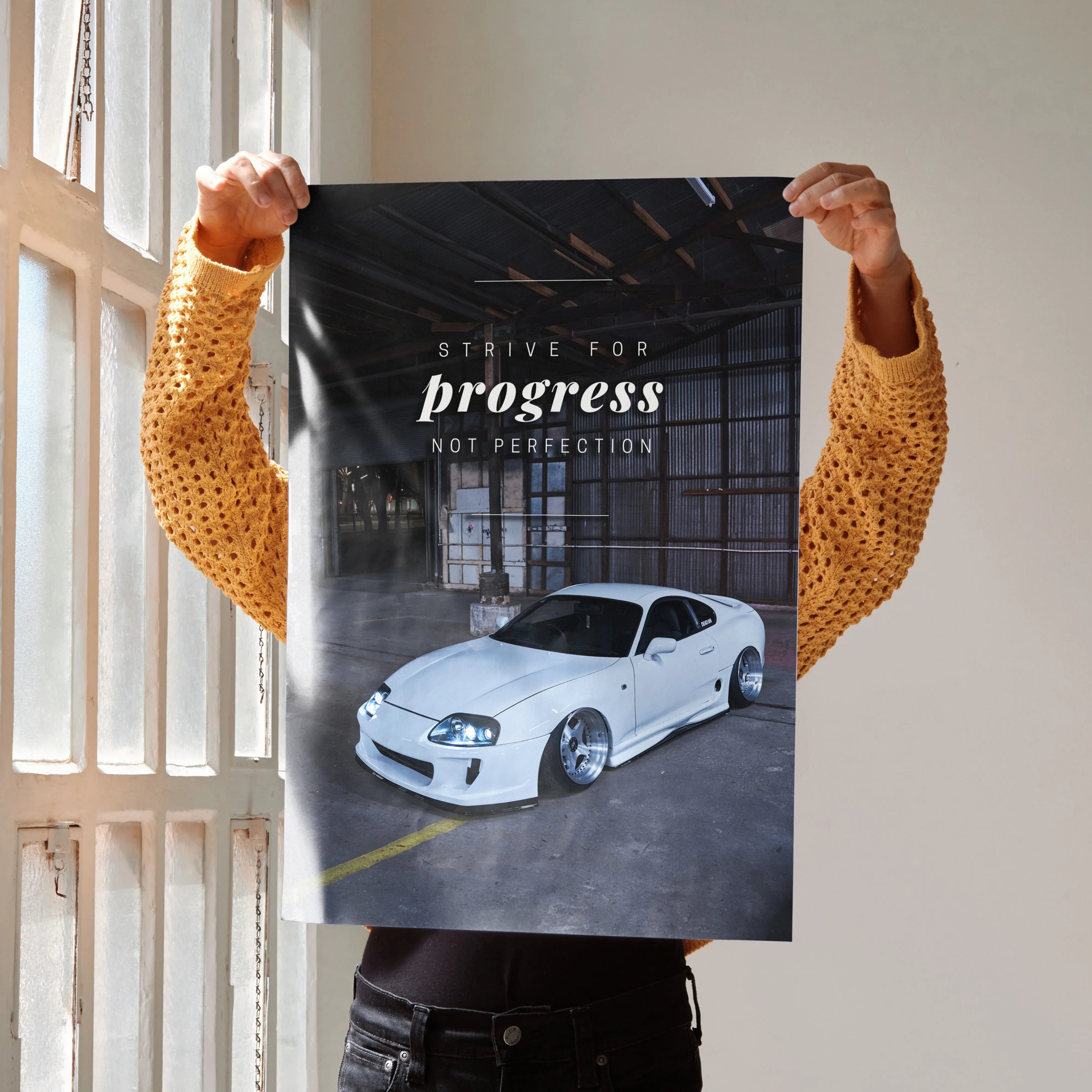 Motivational poster featuring a white Toyota Supra Mk4 under dim industrial lighting with "Strive for progress not.