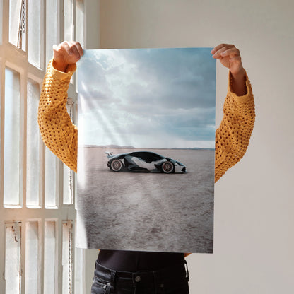 Lamborghini Huracan poster showing sleek black and white sports car on desert ground, wall art with cloudy sky backdrop.