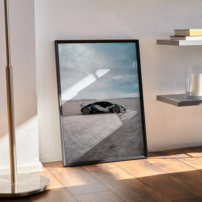 Lamborghini Huracan poster wall art showcasing a sleek black sports car on a light desert landscape under a cloudy sky.