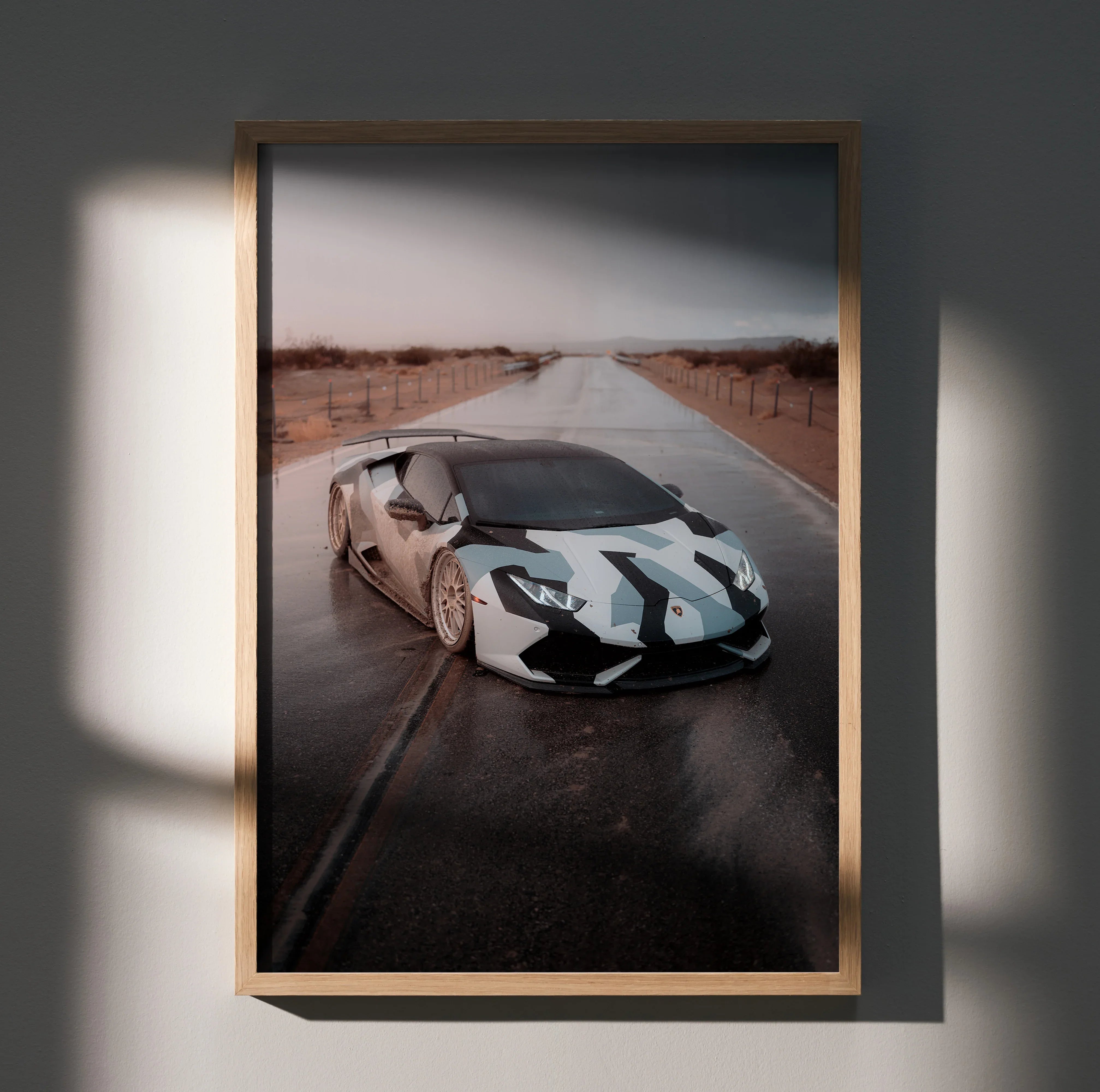 Lamborghini Huracan poster wall art featuring a white and black sports car on a wet desert road with wooden frame.