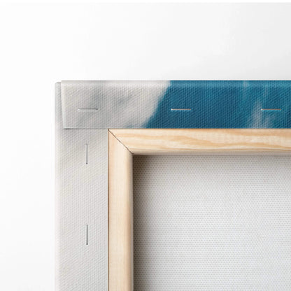 Close-up of wooden frame and stapled corner of canvas wall art with blue and white painted edge visible.
