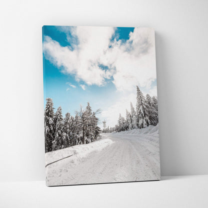Canvas wall art featuring a snowy landscape with frosted evergreen trees under a bright blue sky with white clouds.