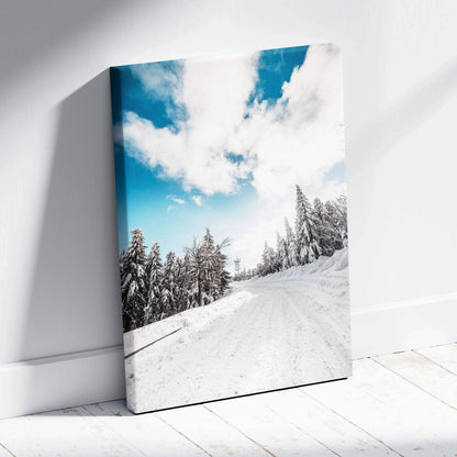Canvas wall art featuring a snowy winter landscape with frosted trees under a bright blue sky with white clouds.