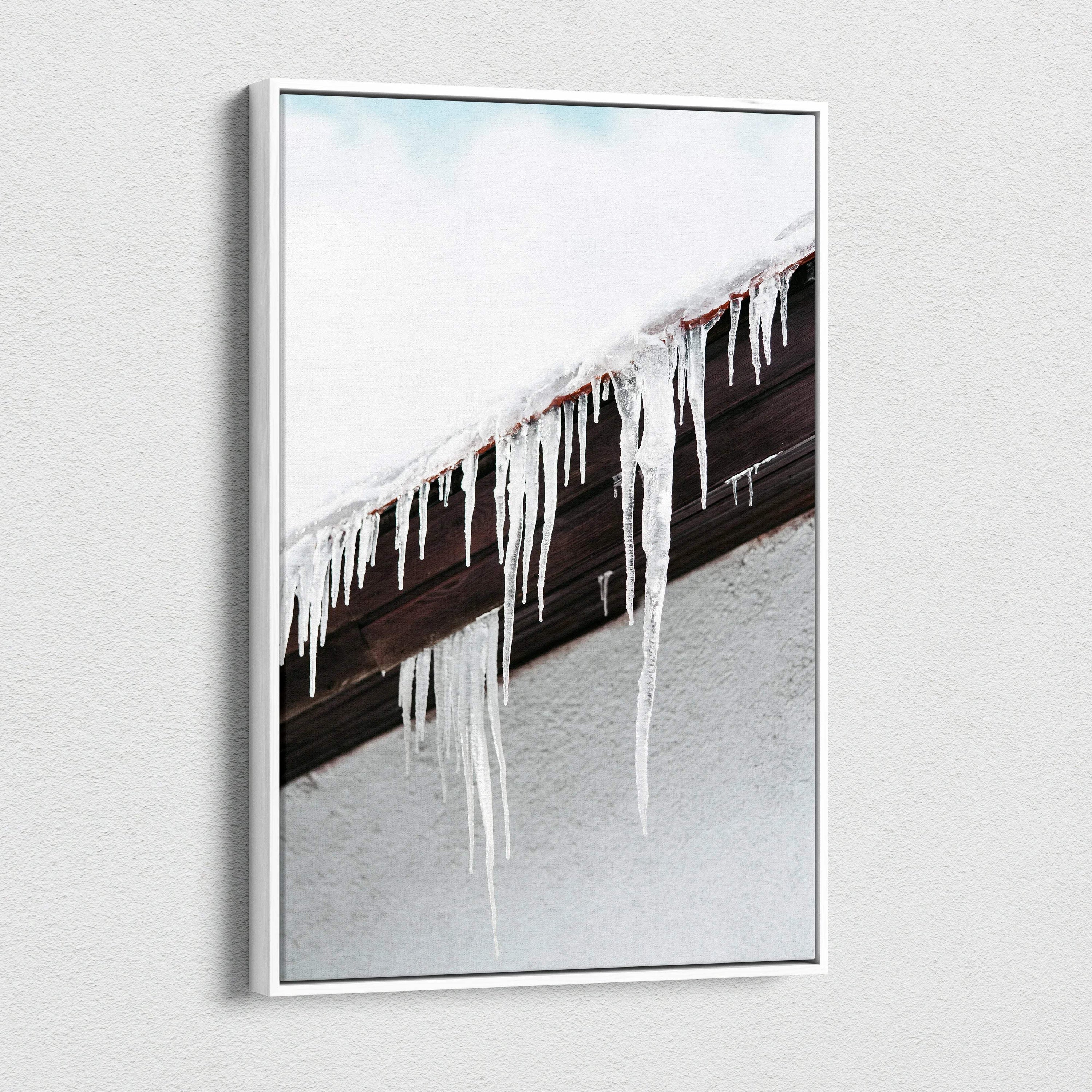 Canvas wall art featuring close-up of long, clear icicles hanging from a snow-covered dark brown roof edge against a pale.