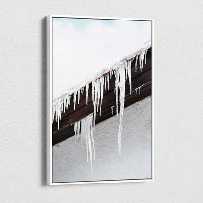 Canvas wall art featuring close-up of long, clear icicles hanging from a snow-covered dark brown roof edge against a pale.
