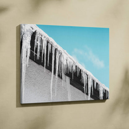 Canvas wall art featuring long winter icicles hanging from a snowy rooftop against a clear blue sky for seasonal decor.