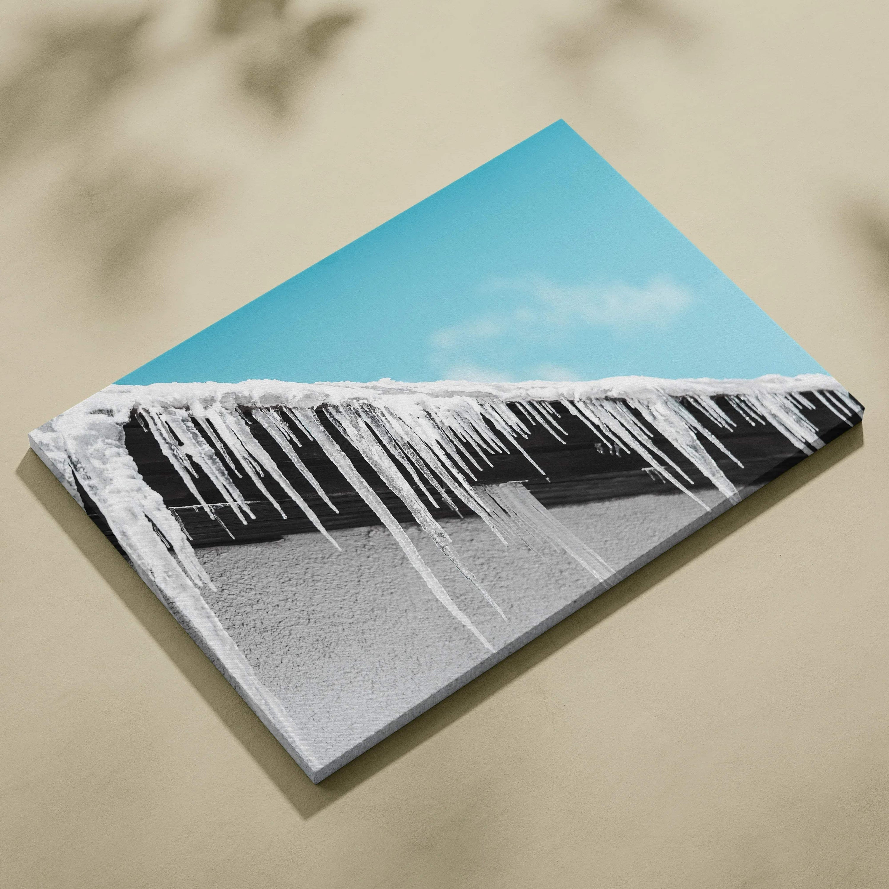 Canvas wall art featuring long, sharp white icicles hanging from a snow-covered roof under a bright blue sky.