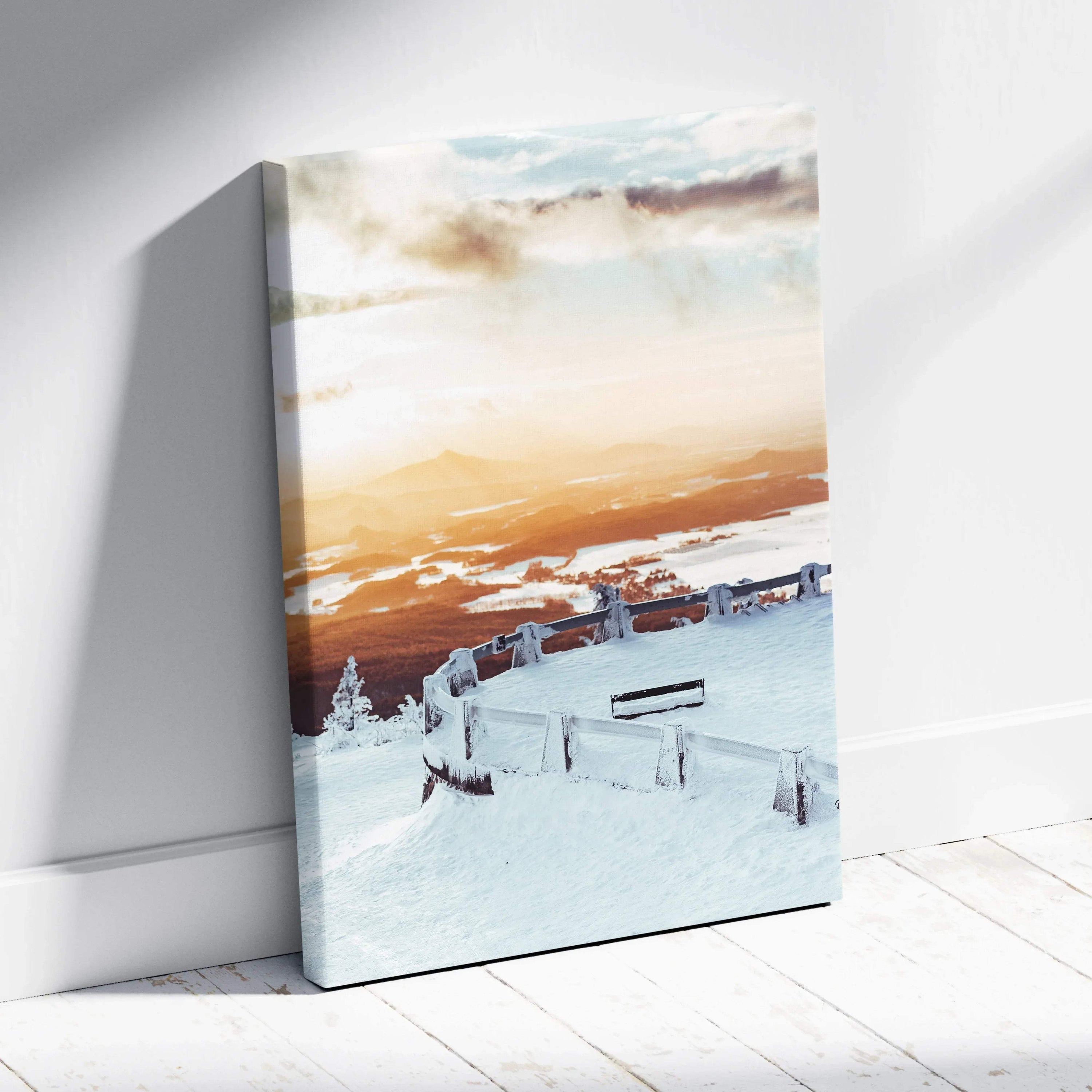 Canvas wall art featuring a snowy winter landscape at sunset with warm orange skies and snow-covered benches.