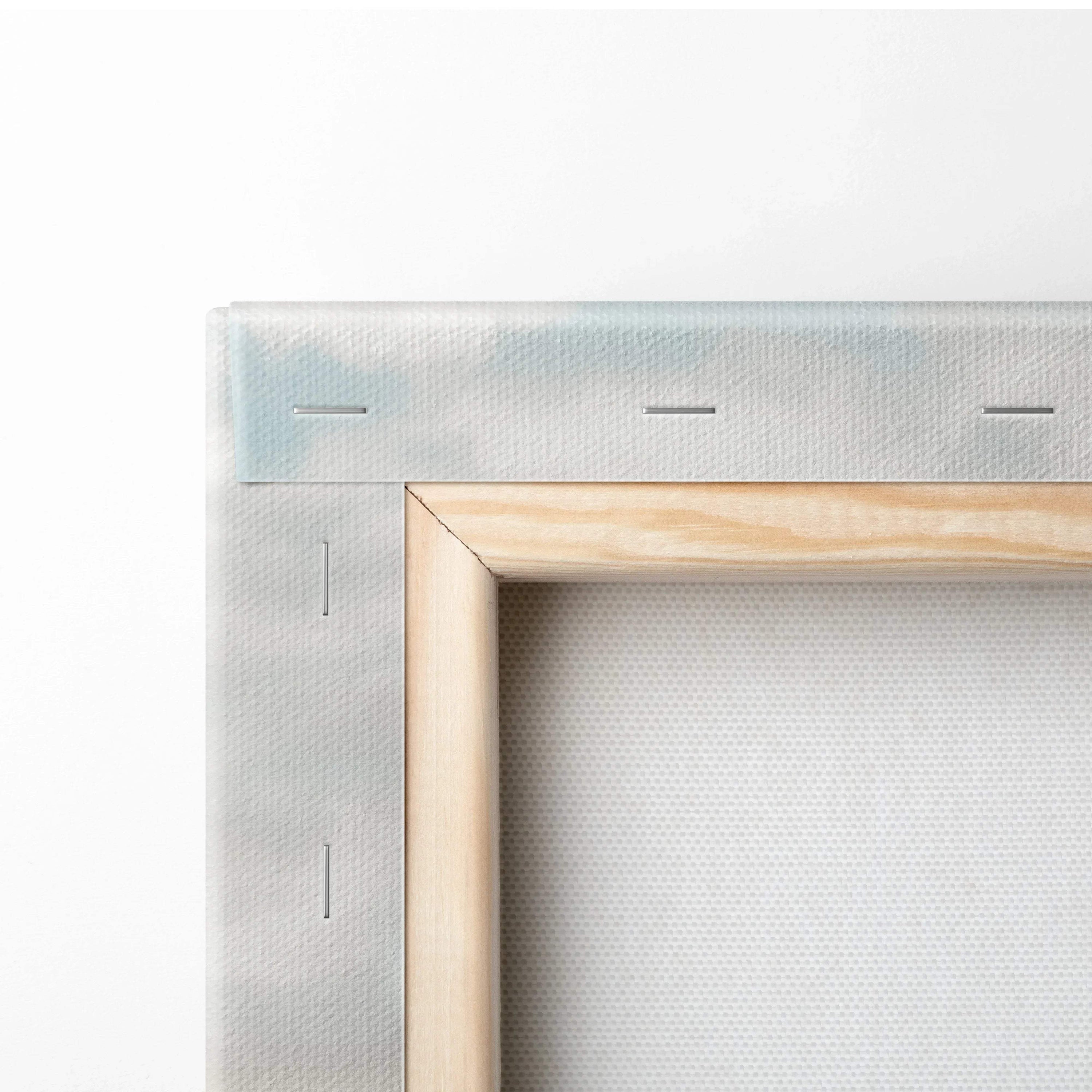 Close-up of canvas wall art showing light wooden frame and white fabric stretched and stapled around edges for home decor.