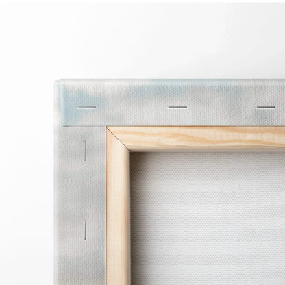 Close-up of canvas wall art showing light wooden frame and white fabric stretched and stapled around edges for home decor.