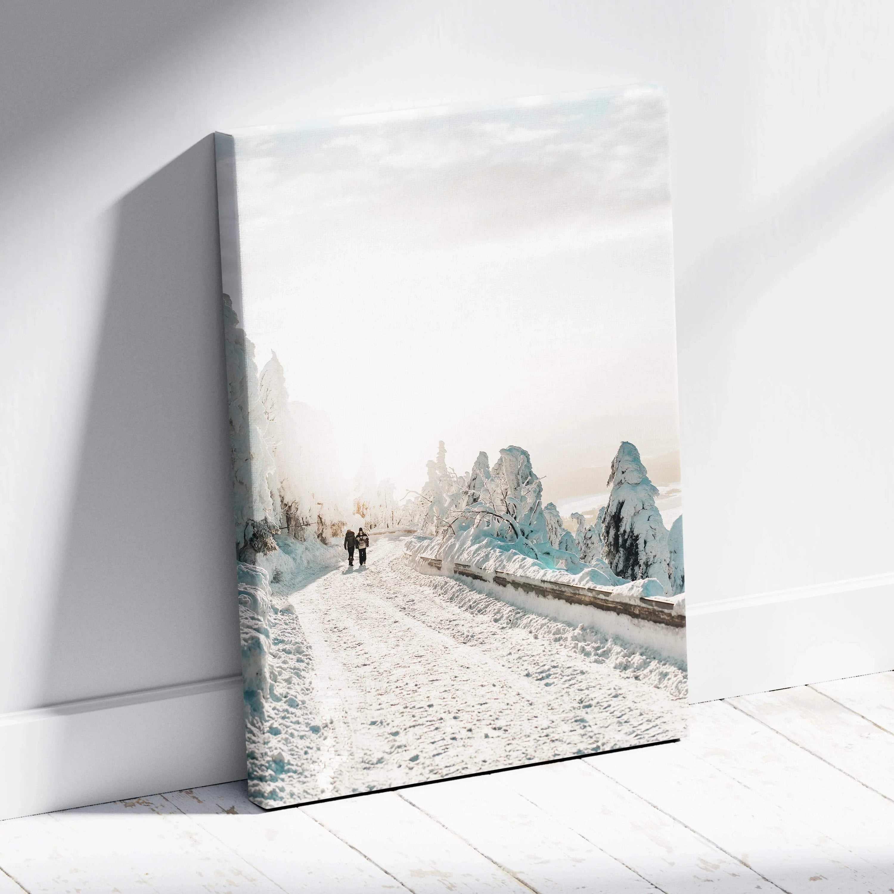 Canvas wall art featuring a serene snowy road flanked by snow-covered trees in soft winter tones.