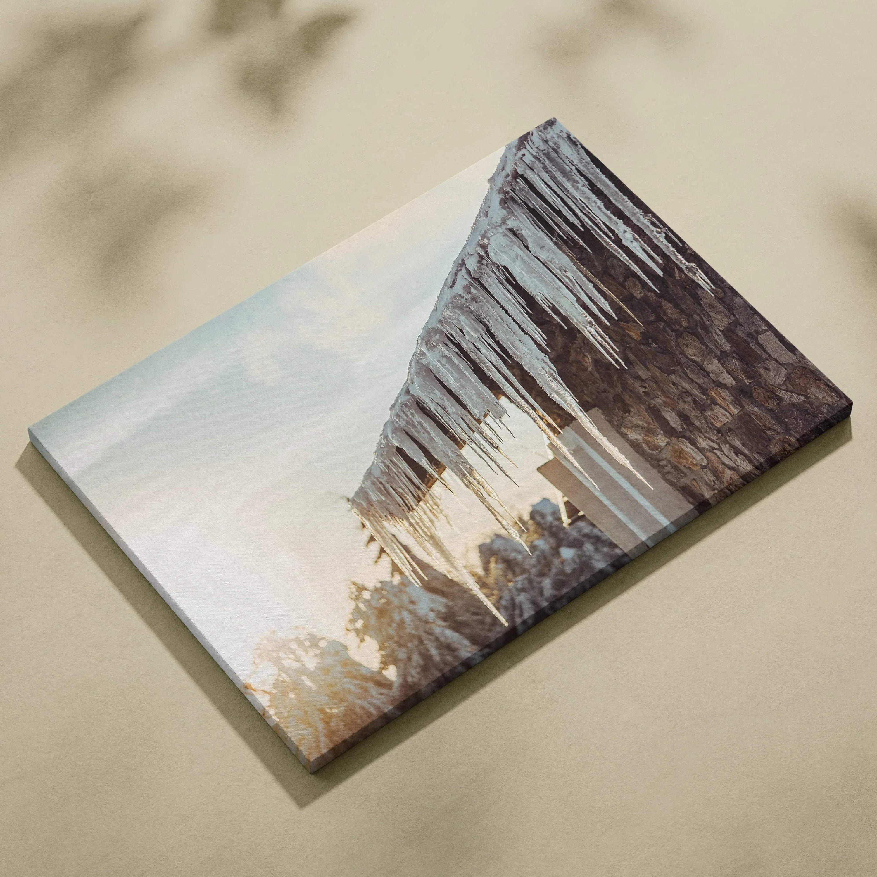 Canvas wall art featuring digital winter scene with long, glistening icicles hanging from a rustic roof against a light sky.
