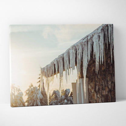 Canvas wall art featuring detailed digital winter scene with long glistening icicles hanging from rustic stone roof against.