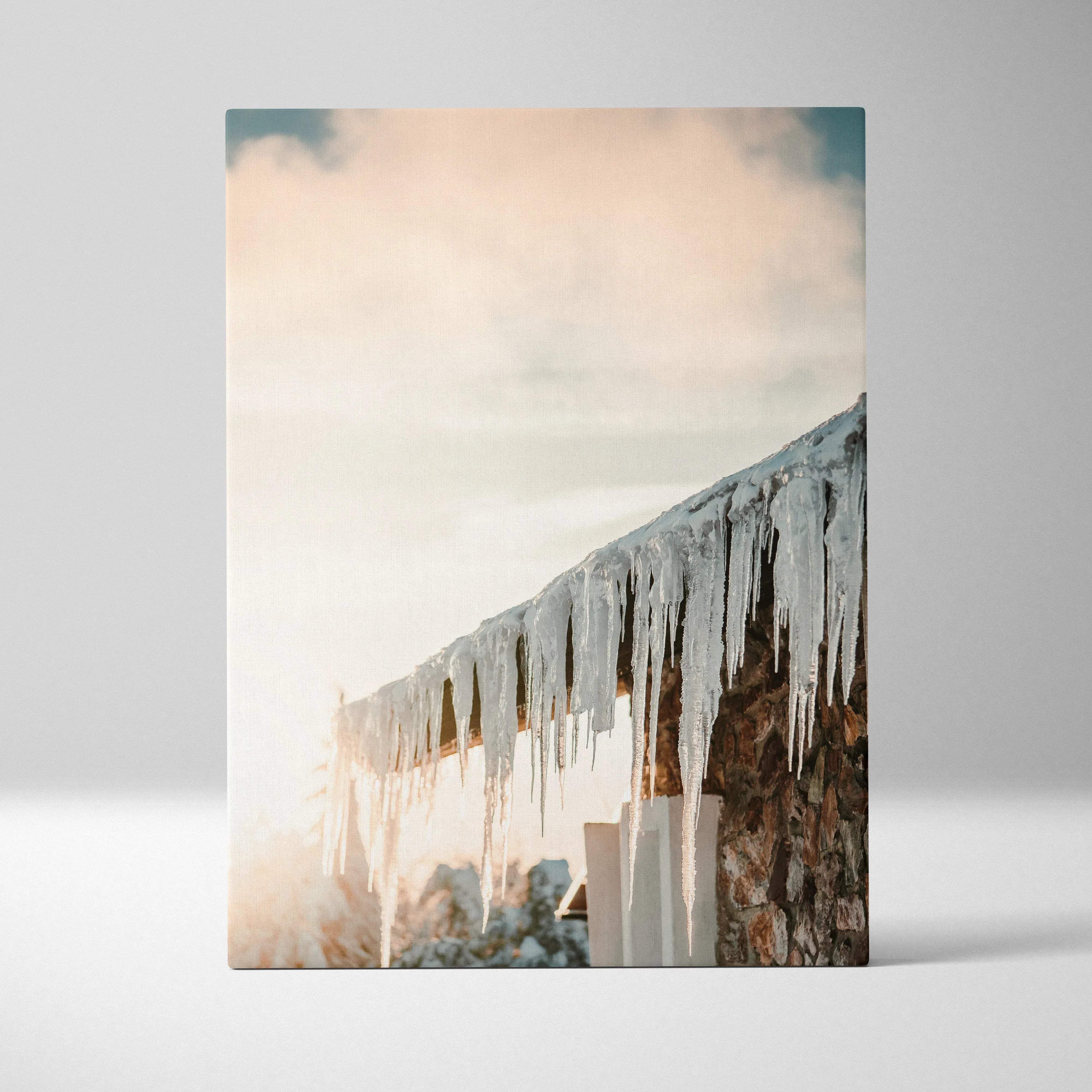 Rectangular canvas print featuring translucent icicles on a rustic stone roof with soft pastel snowy glow sky