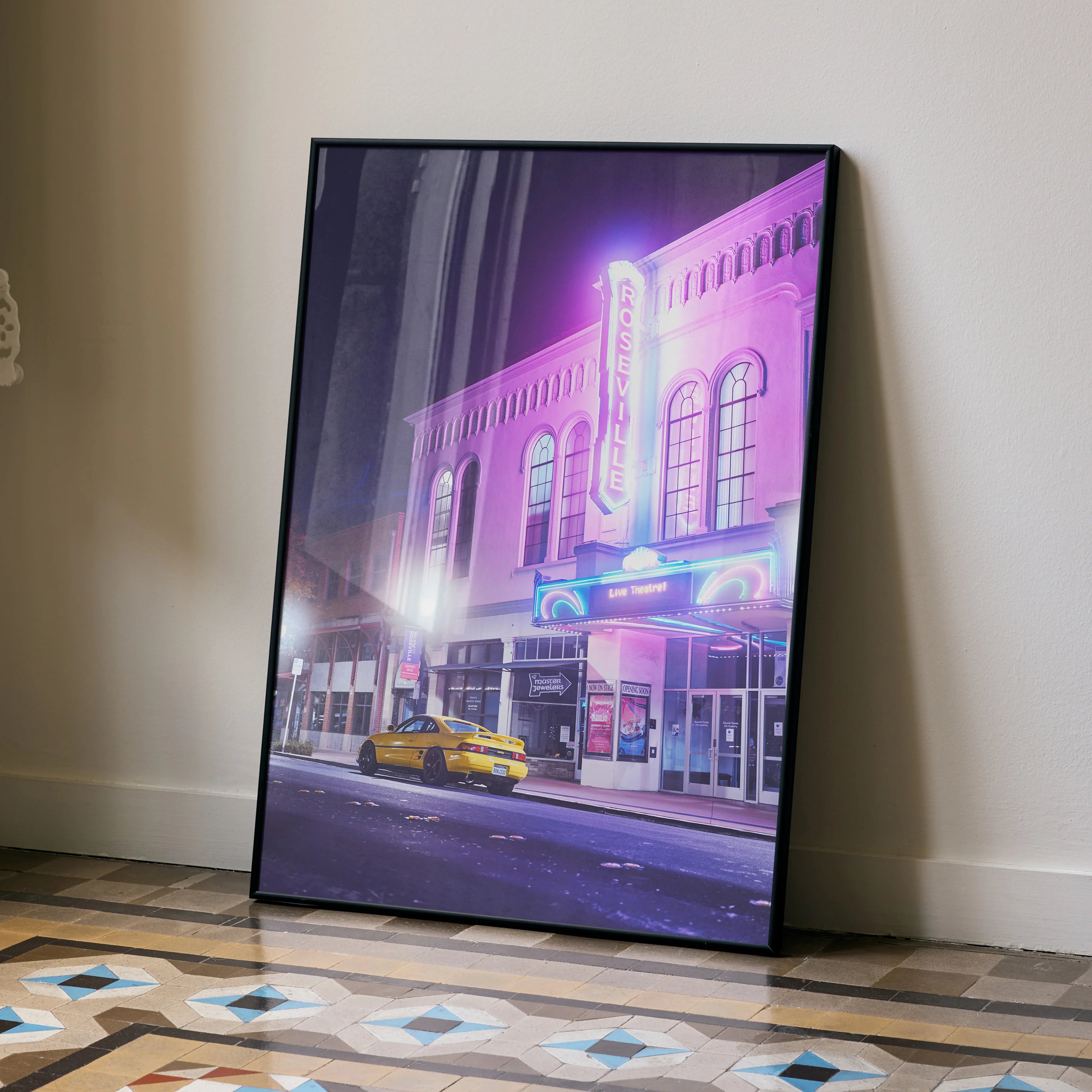 Toyota MR2 parked in front of neon-lit theater, vibrant purple and blue tones poster wall art.