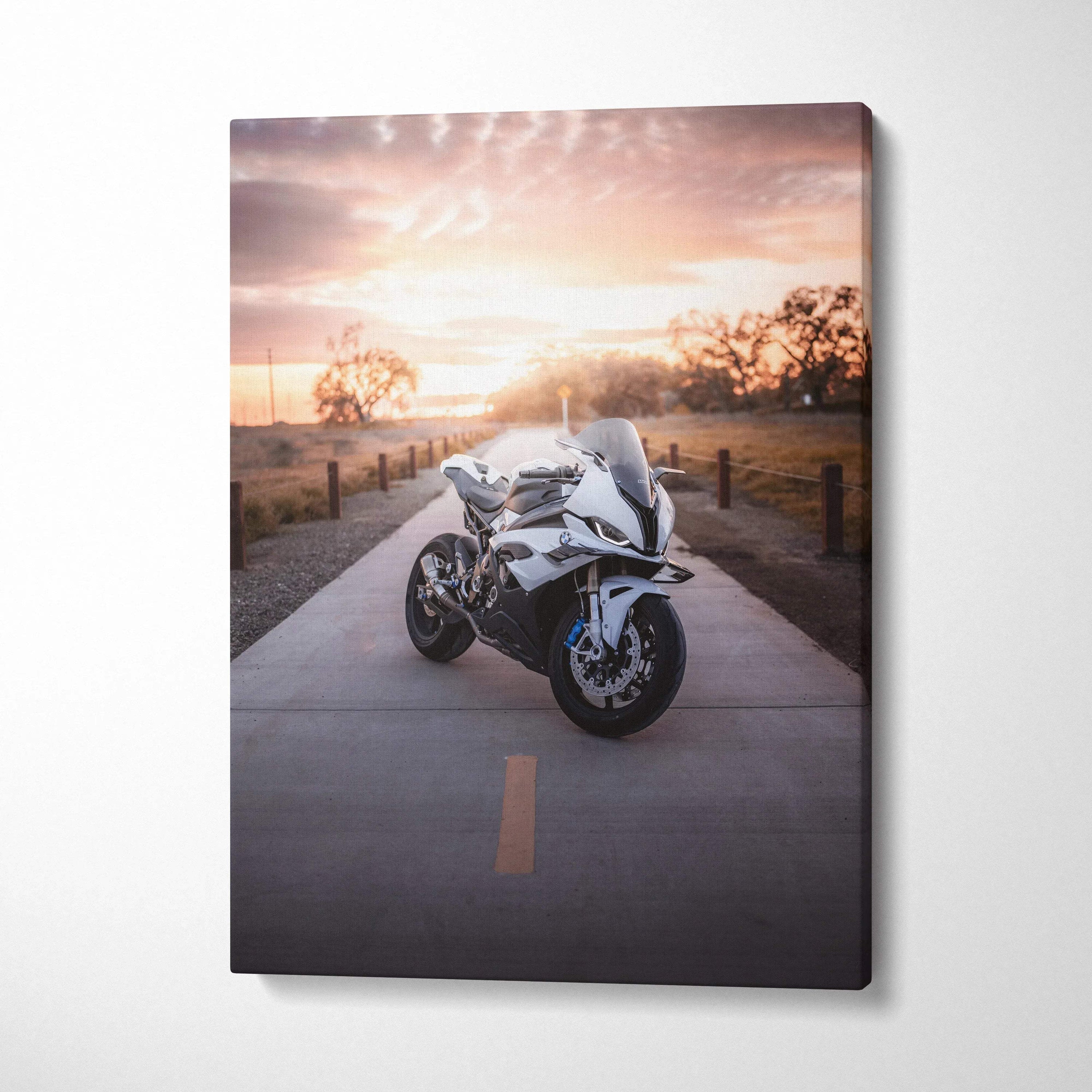Vertical canvas wall art featuring a white BMW S1000RR motorcycle on a sunset-lit road.