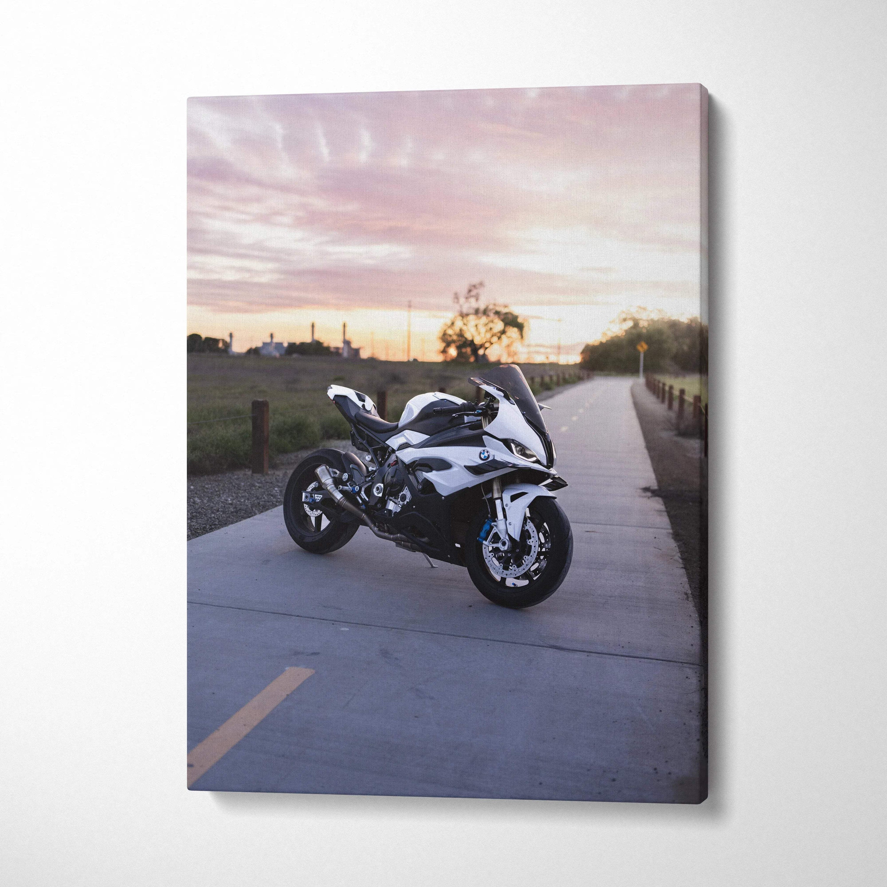 Vertical canvas wall art featuring a BMW S1000RR motorcycle at sunset on a roadside path.