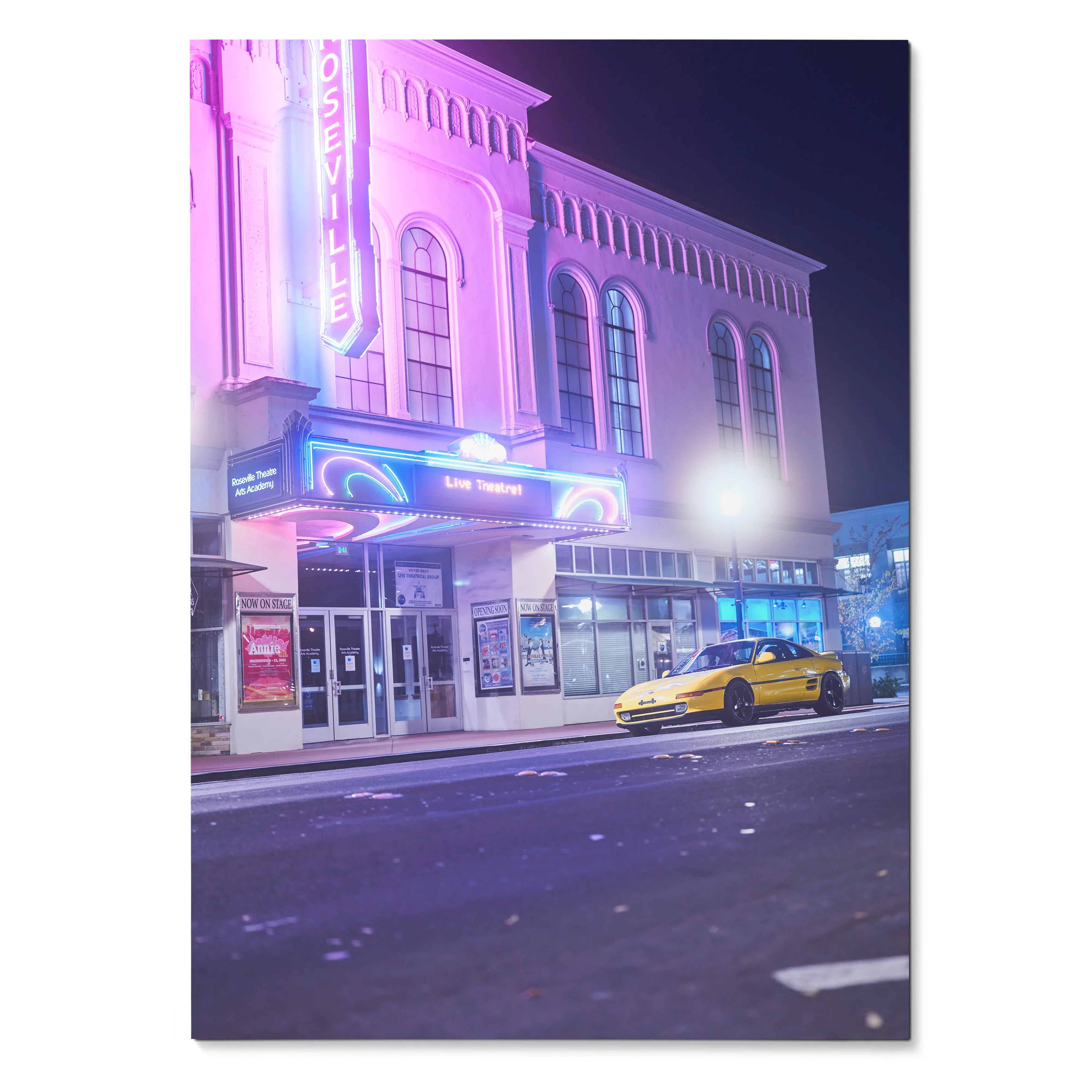 Toyota MR2 yellow sports car parked outside neon-lit theater at night poster wall art.