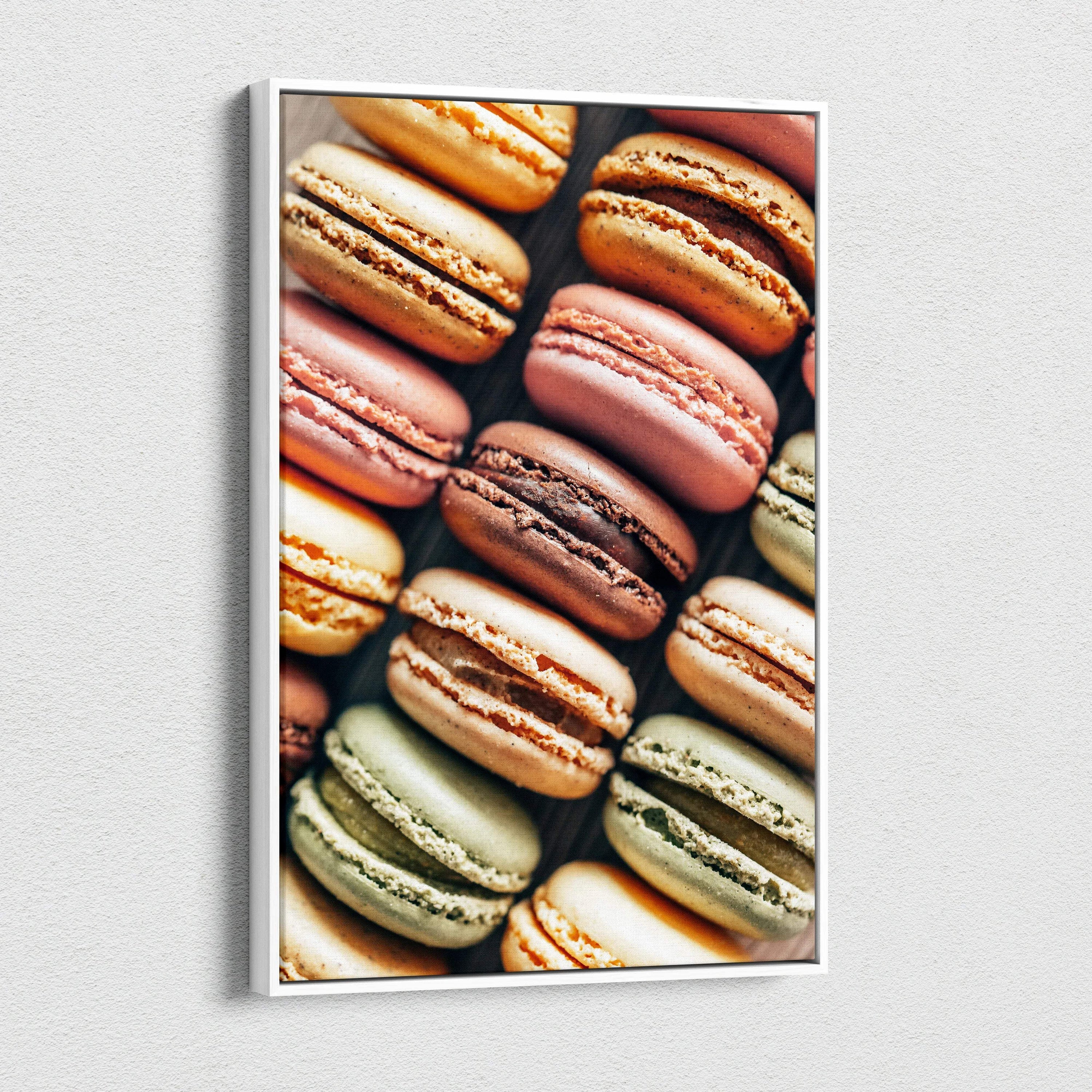 Canvas wall art featuring colorful macarons in shades of brown, pink, green, and cream, arranged in a grid pattern.