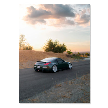 Nissan 350z black sports car on road at sunset poster wall art with scenic sky background.