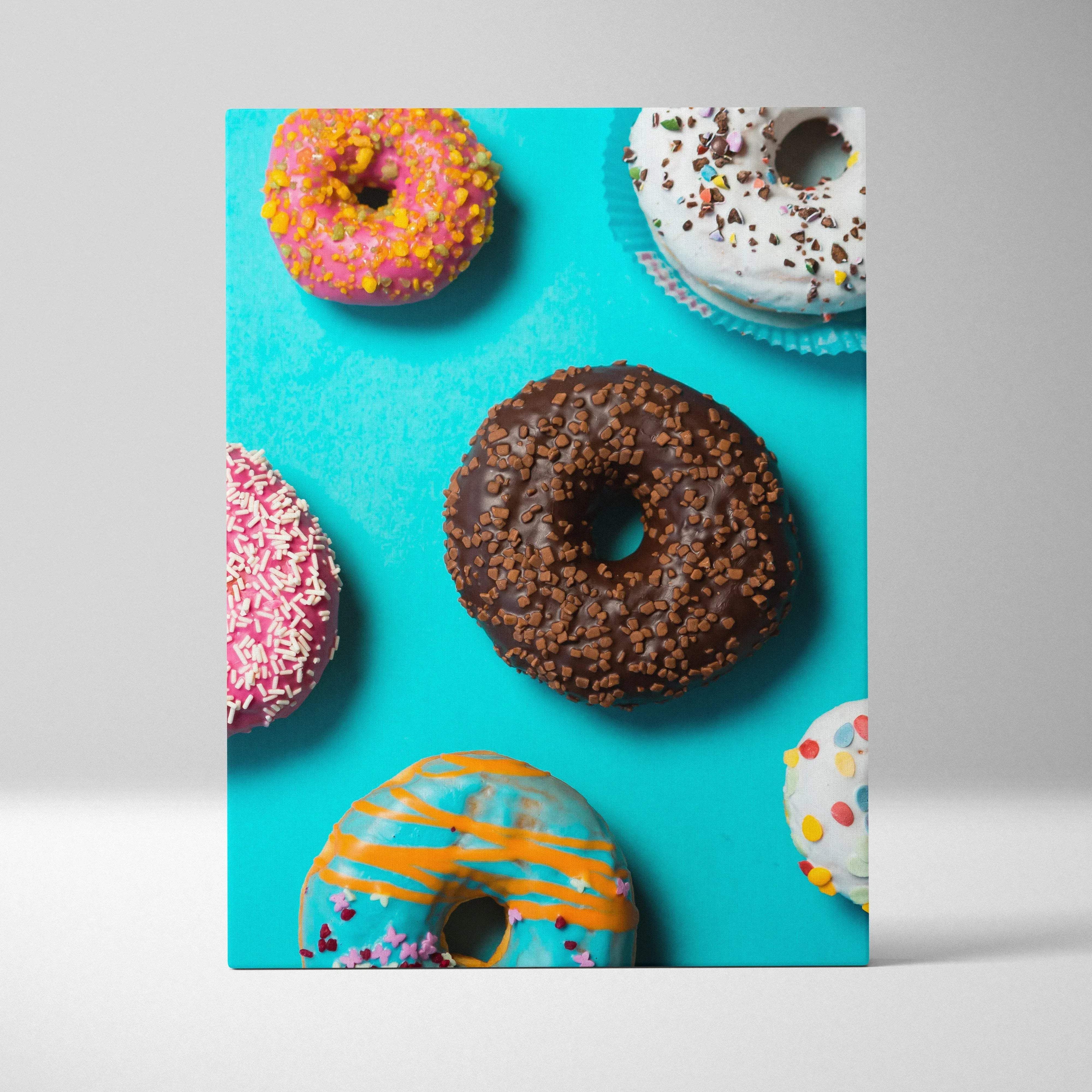 A vibrant turquoise canvas print of assorted colorful frosted donuts with sprinkles for bright pop art wall decor