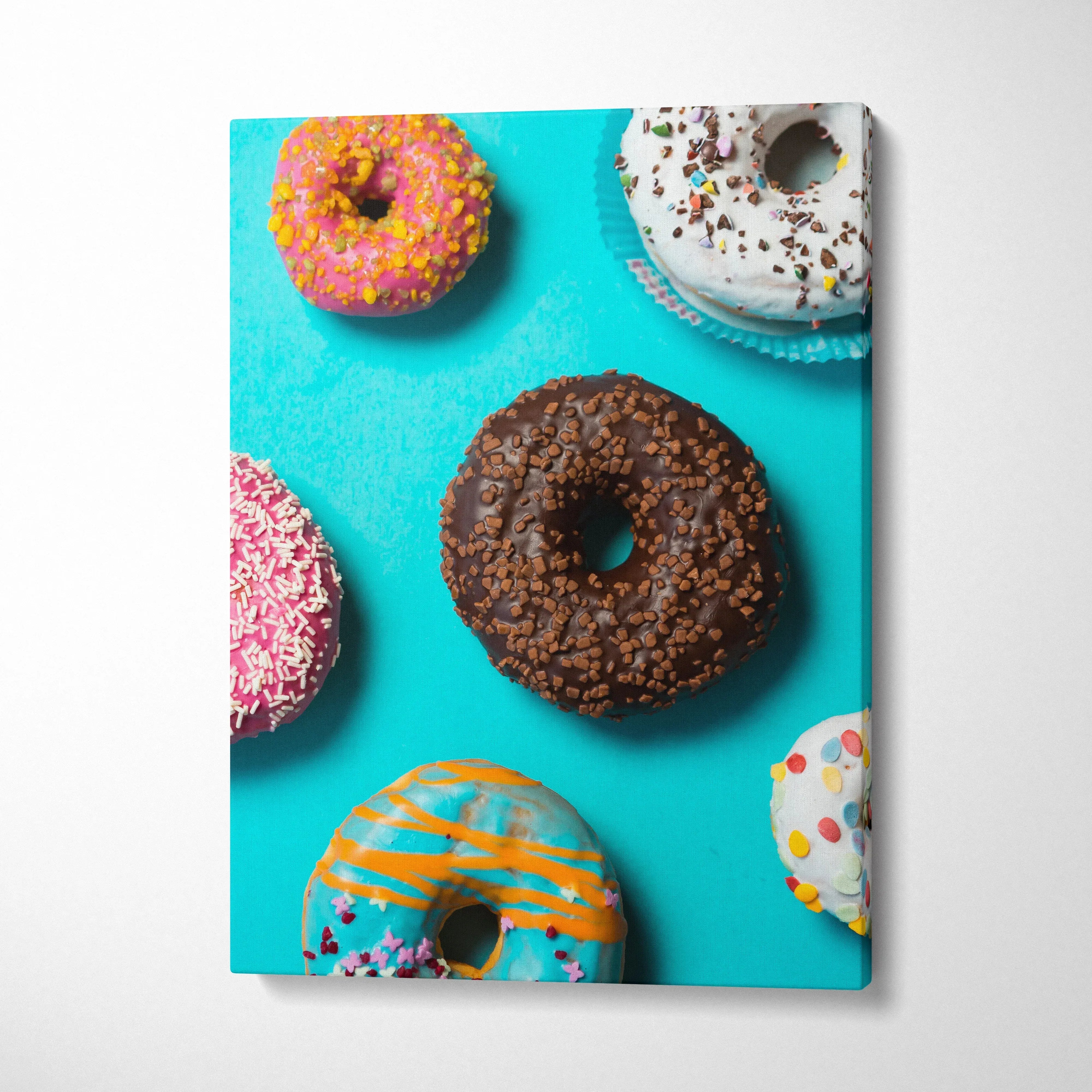 Canvas wall art featuring colorful donuts with sprinkles on a bright turquoise background for kitchen decor.