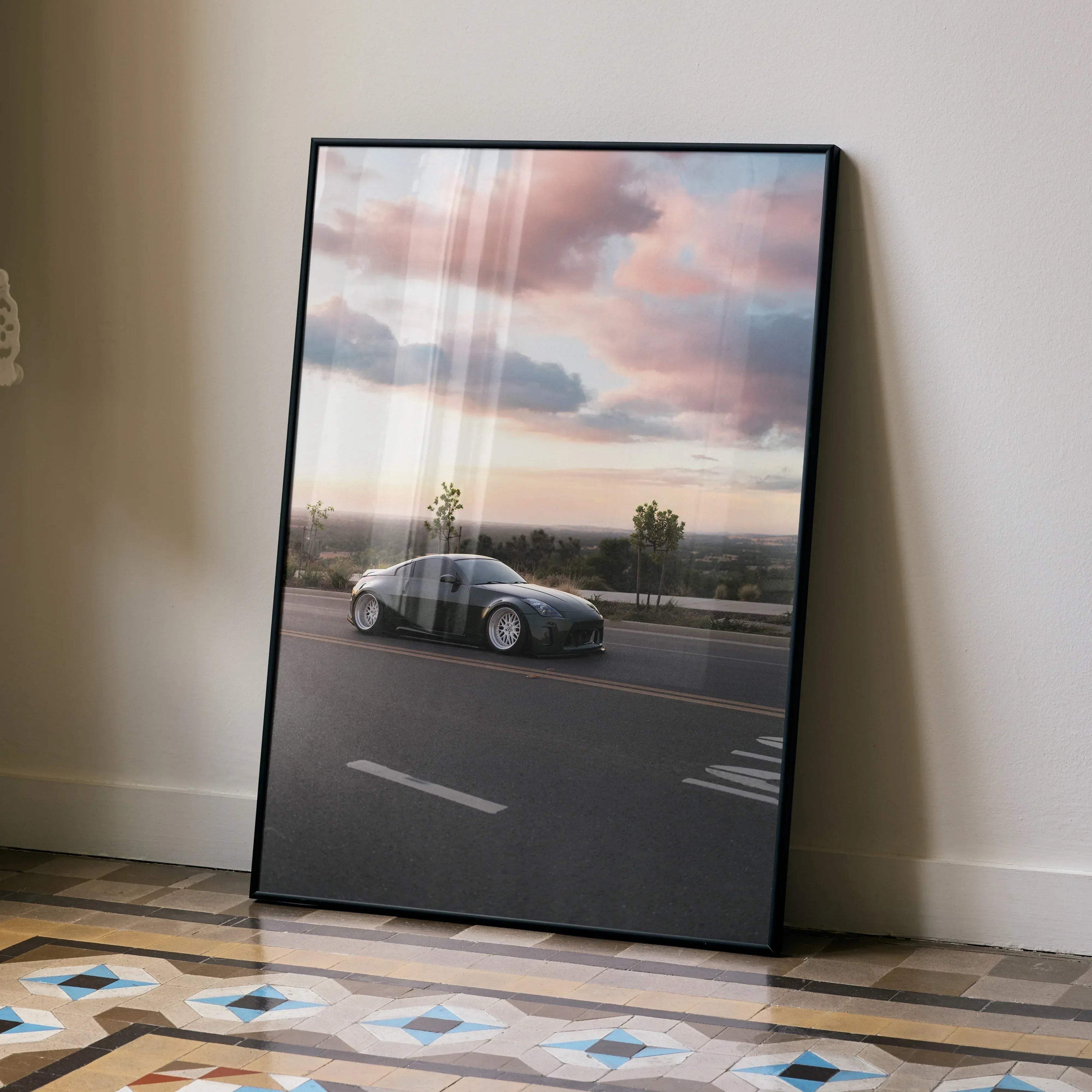Nissan 350z driving at sunset wall art poster with pink and purple clouds in black frame.