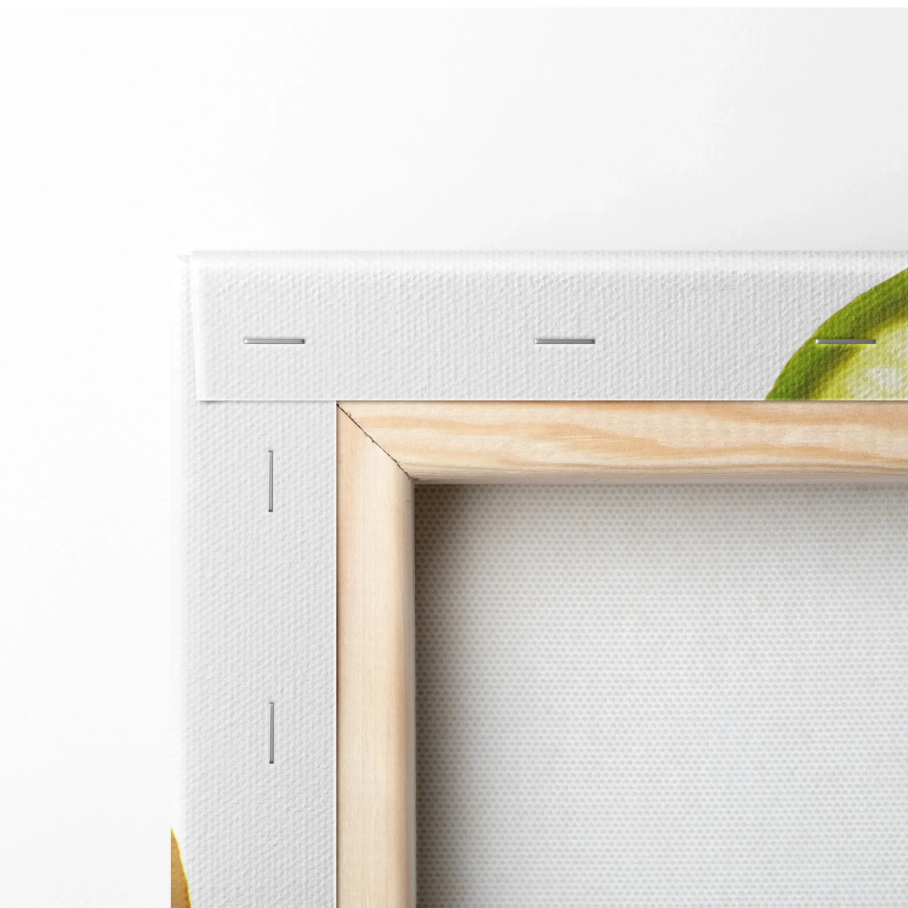 Close-up of stretched canvas art corner with wooden frame and vibrant yellow and green lemon and lime print.