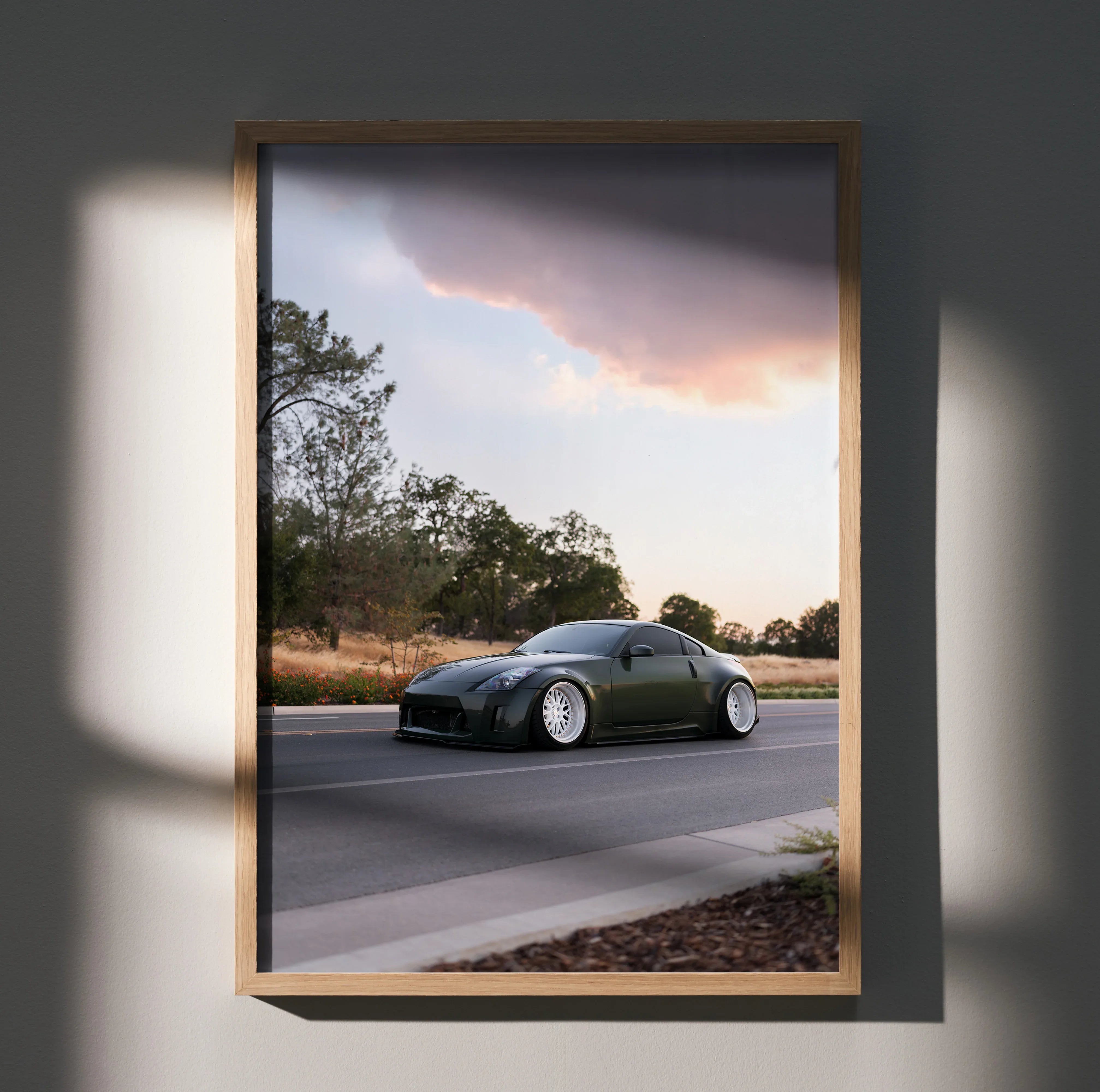 Nissan 350z driving on road at sunset poster wall art in wooden frame.