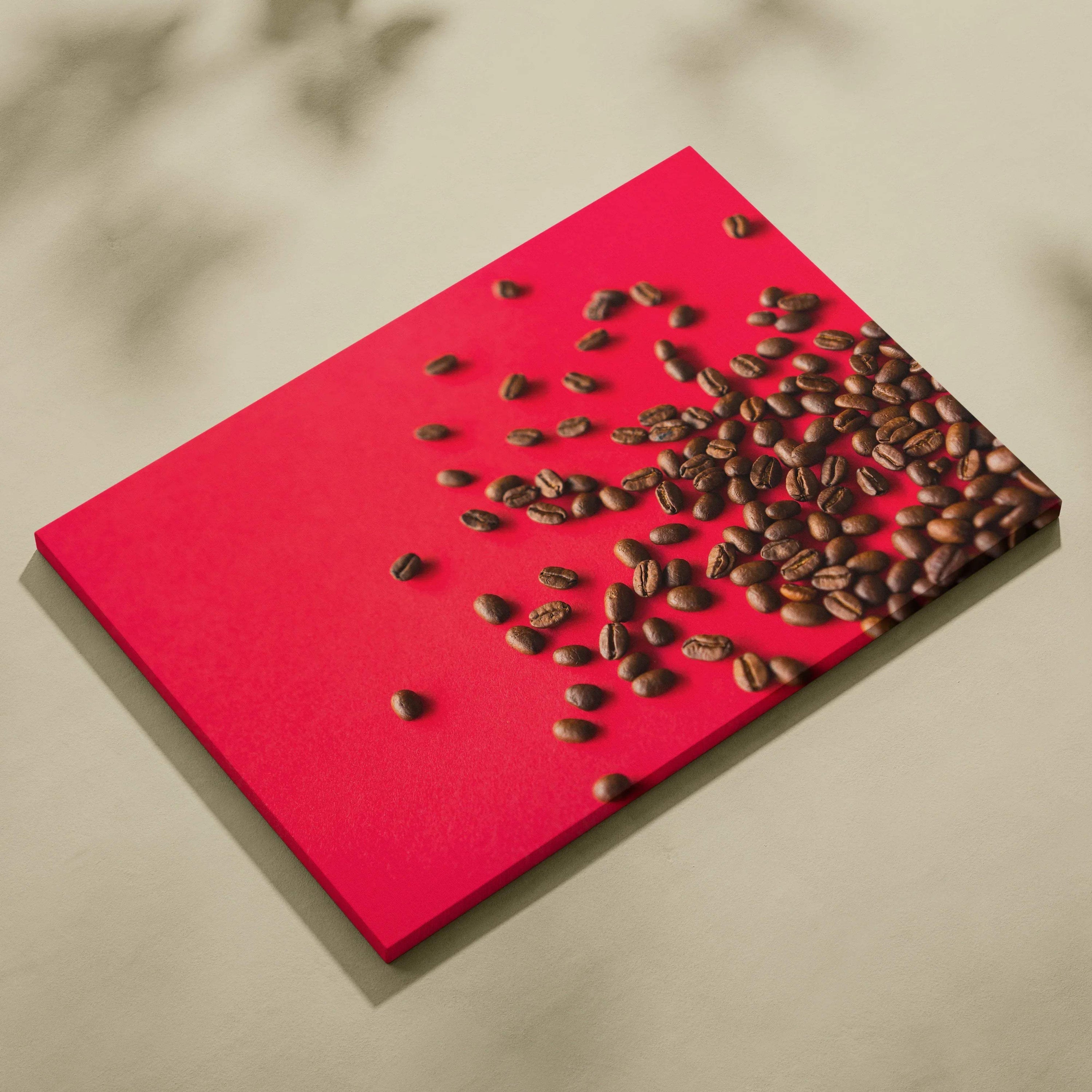 Canvas wall art featuring scattered dark brown coffee beans on a vibrant red background.