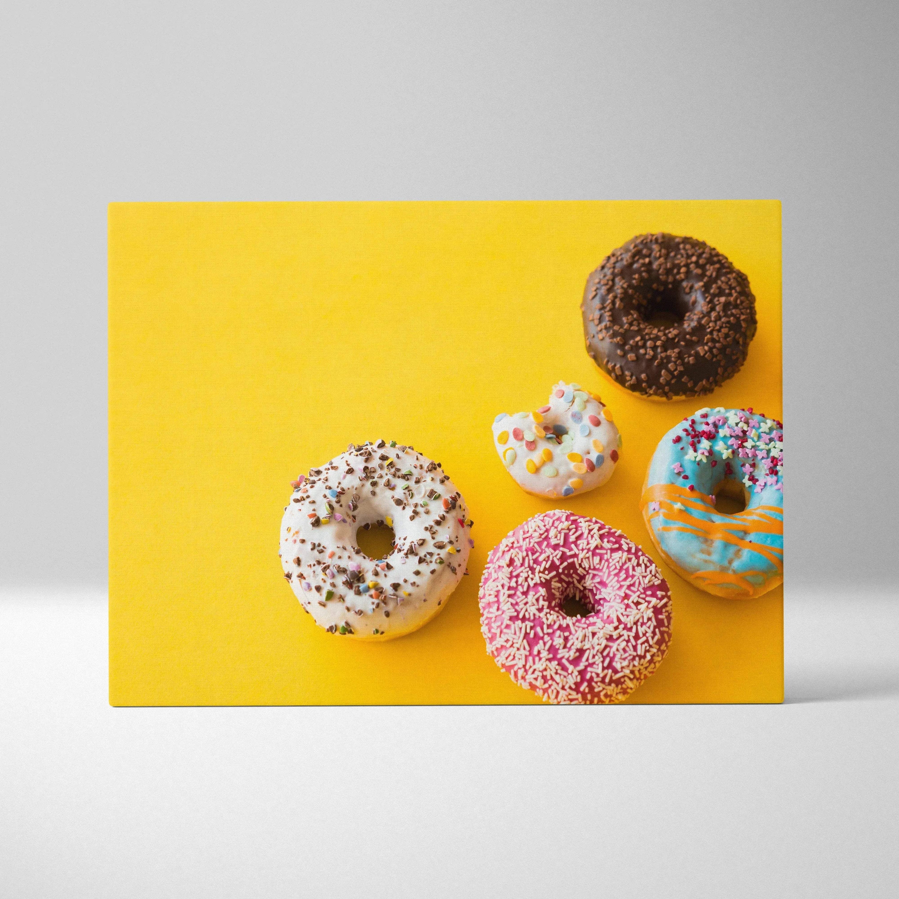 Canvas wall art featuring five colorful donuts with vibrant glazes and sprinkles on a bright yellow background.