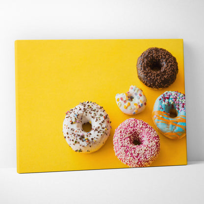 Canvas wall art decor featuring colorful glazed donuts with sprinkles on bright yellow background.