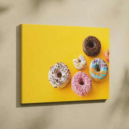 Canvas wall art featuring colorful donut designs with vibrant glazes and sprinkles on a bright yellow background.