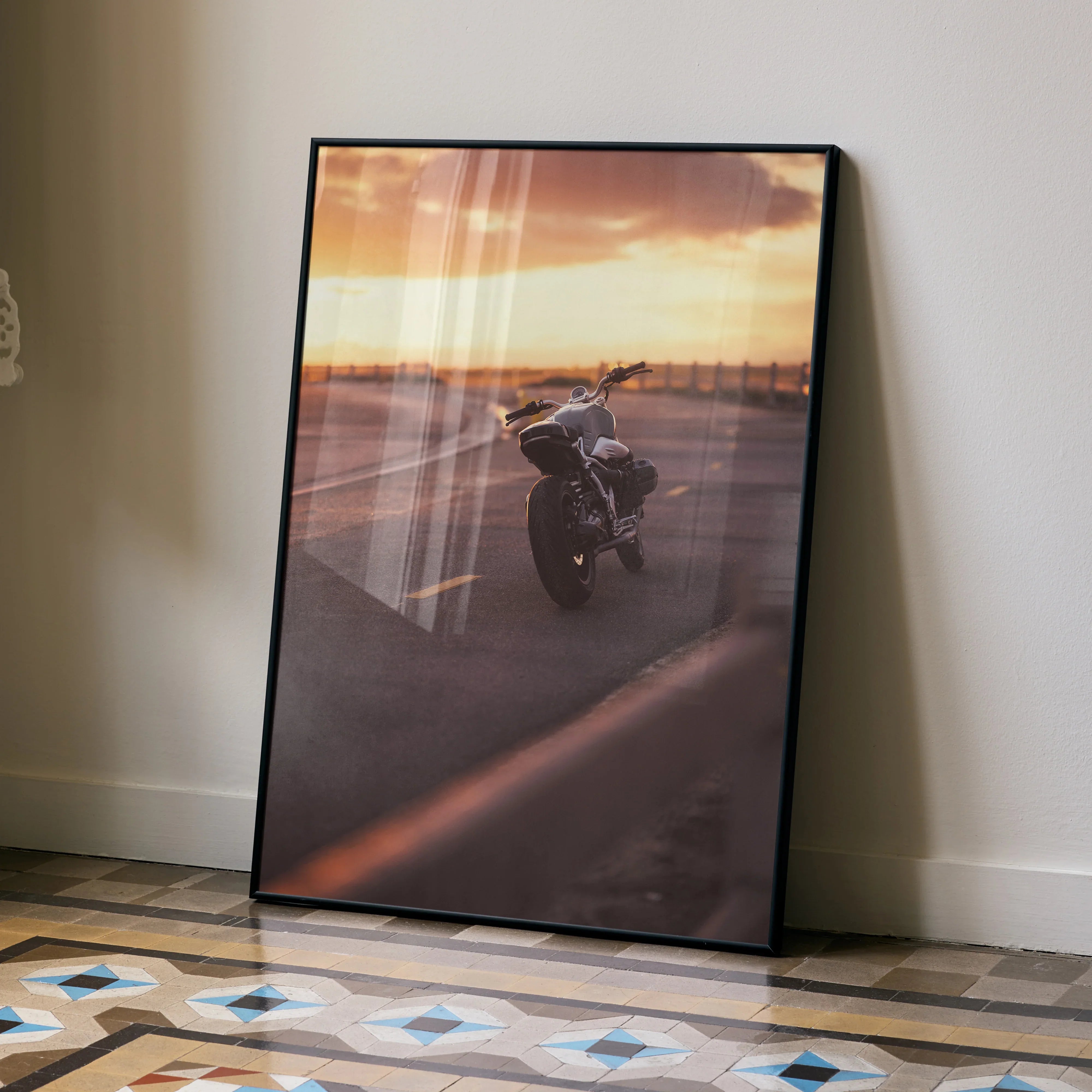 BMW R Nine T motorcycle wall art poster with sunset background in modern black frame leaning on wall.