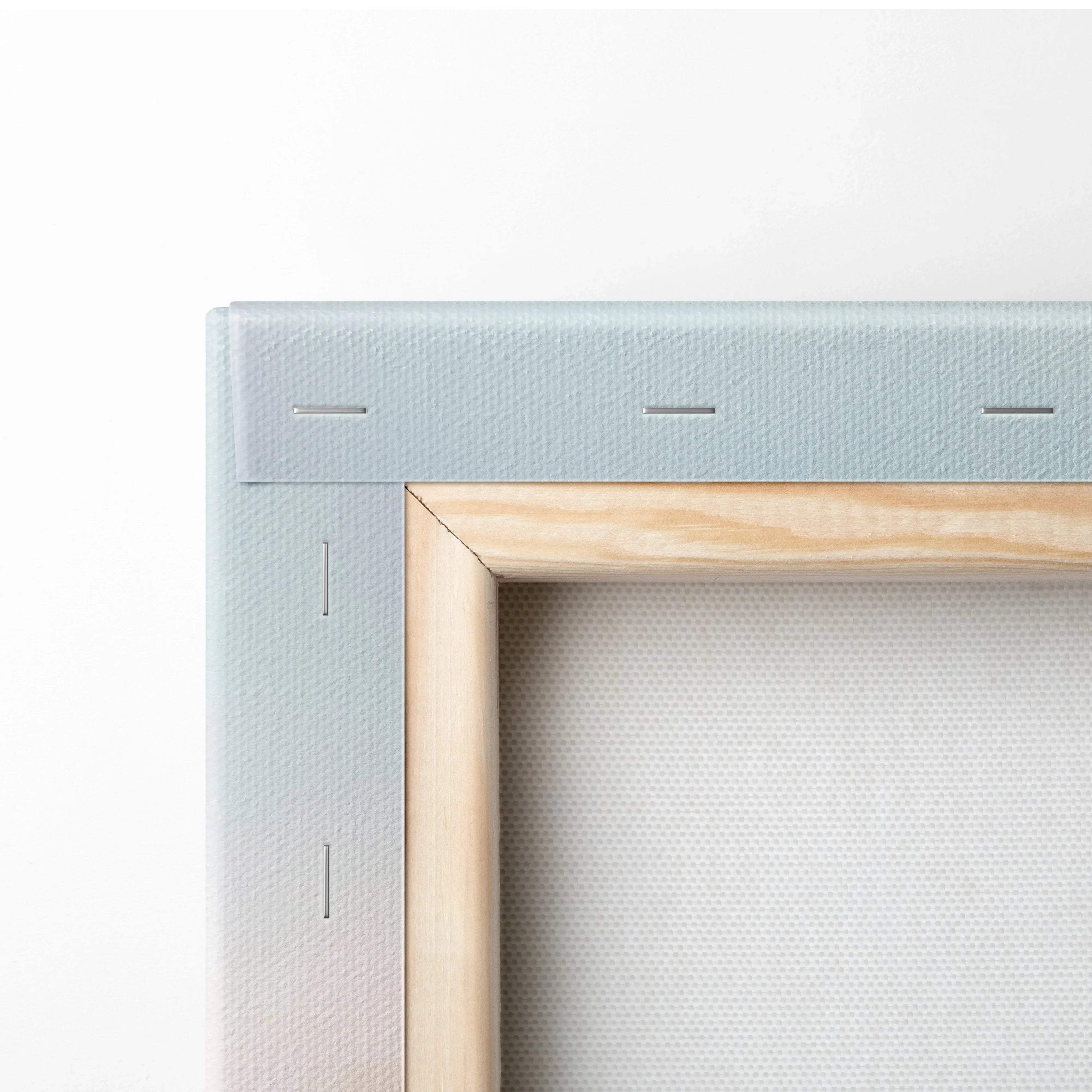 Close-up of corner of stretched canvas wall art with light wood frame and white fabric texture.