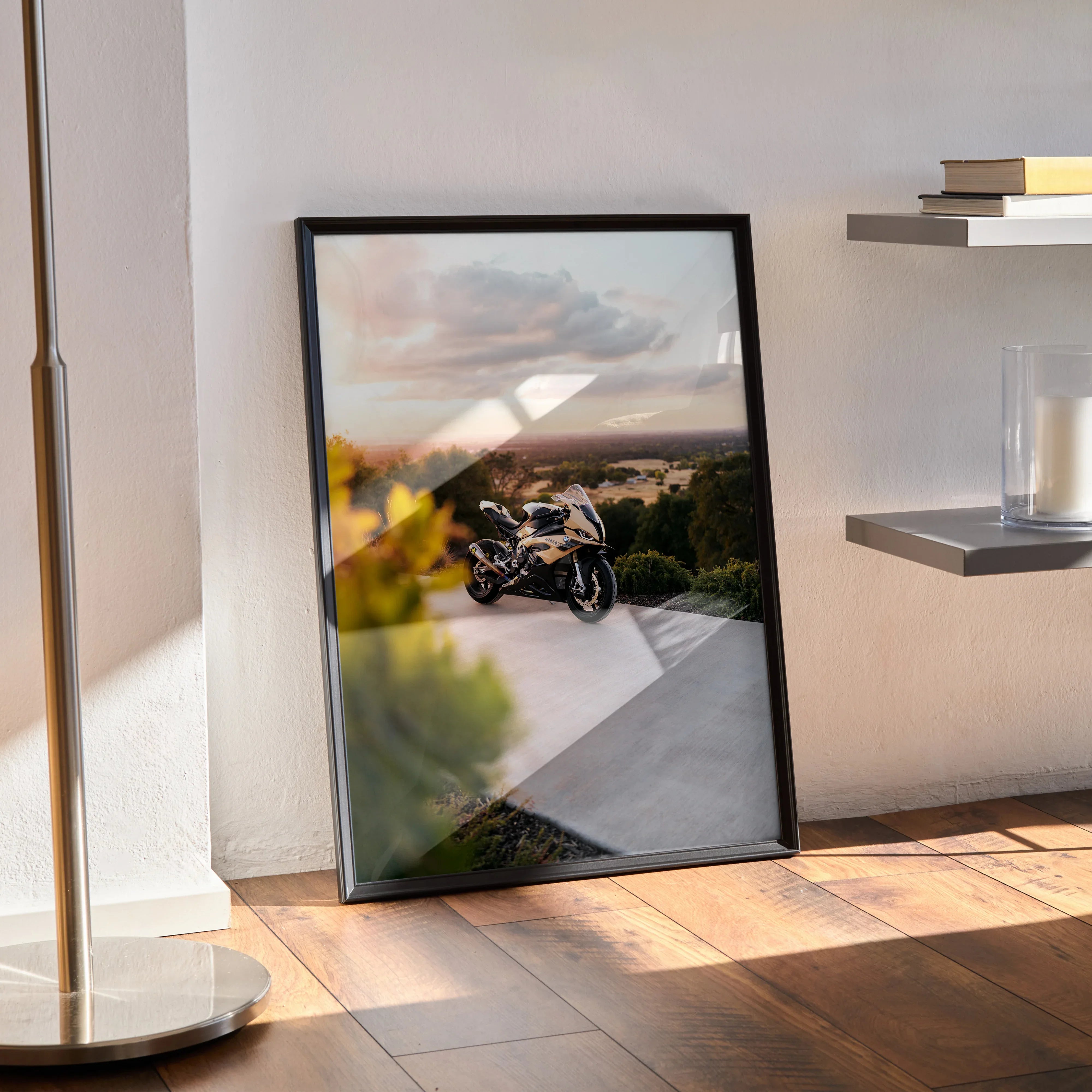 BMW S1000RR motorcycle poster wall art in black frame leaning against white wall on hardwood floor.