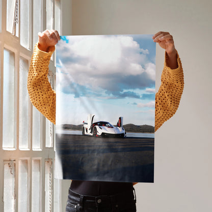 Koenigsegg Jesko poster wall art featuring a sleek white sports car under a blue sky with clouds.