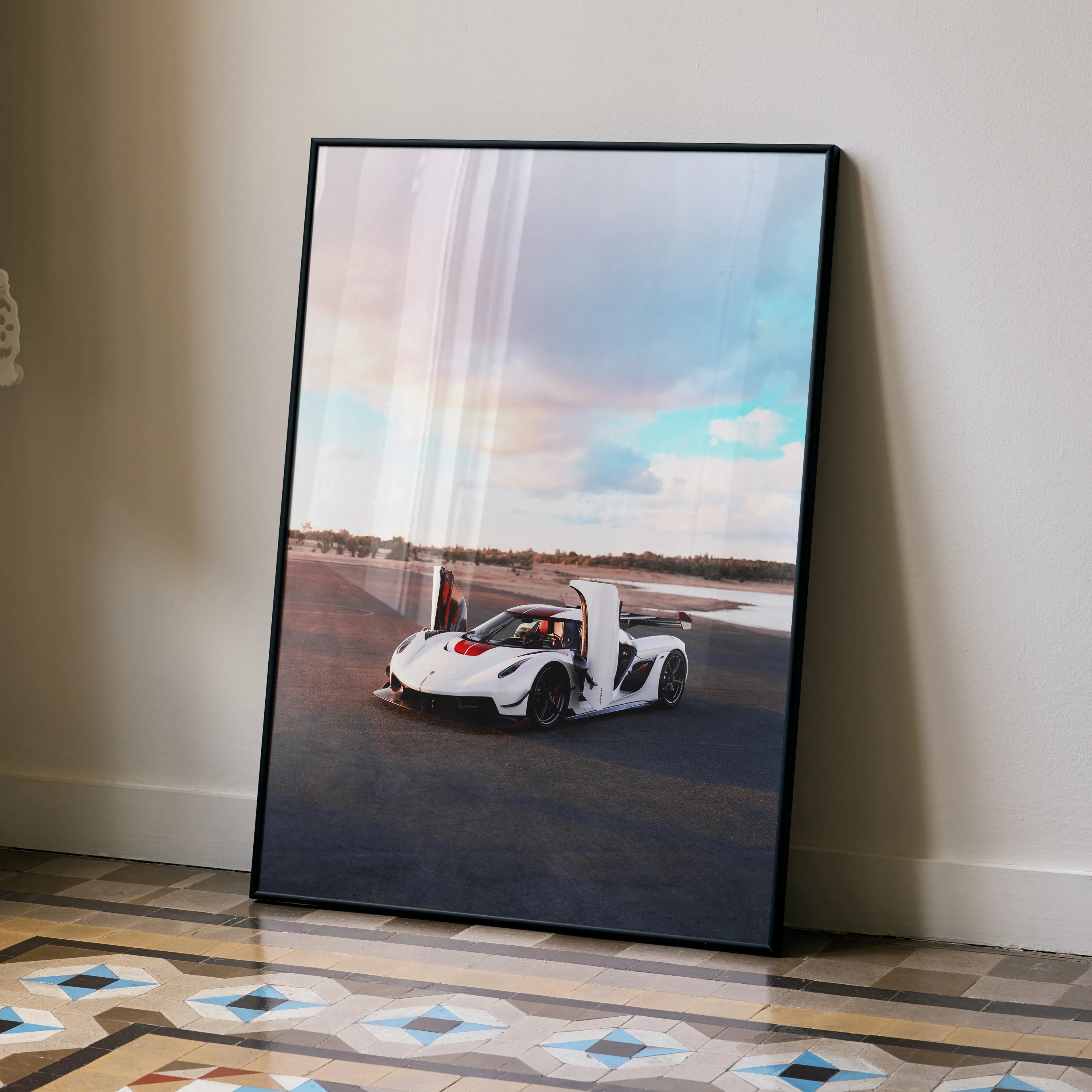 Koenigsegg Jesko poster featuring white sports car with open doors on road under cloudy sky, wall art in black frame.