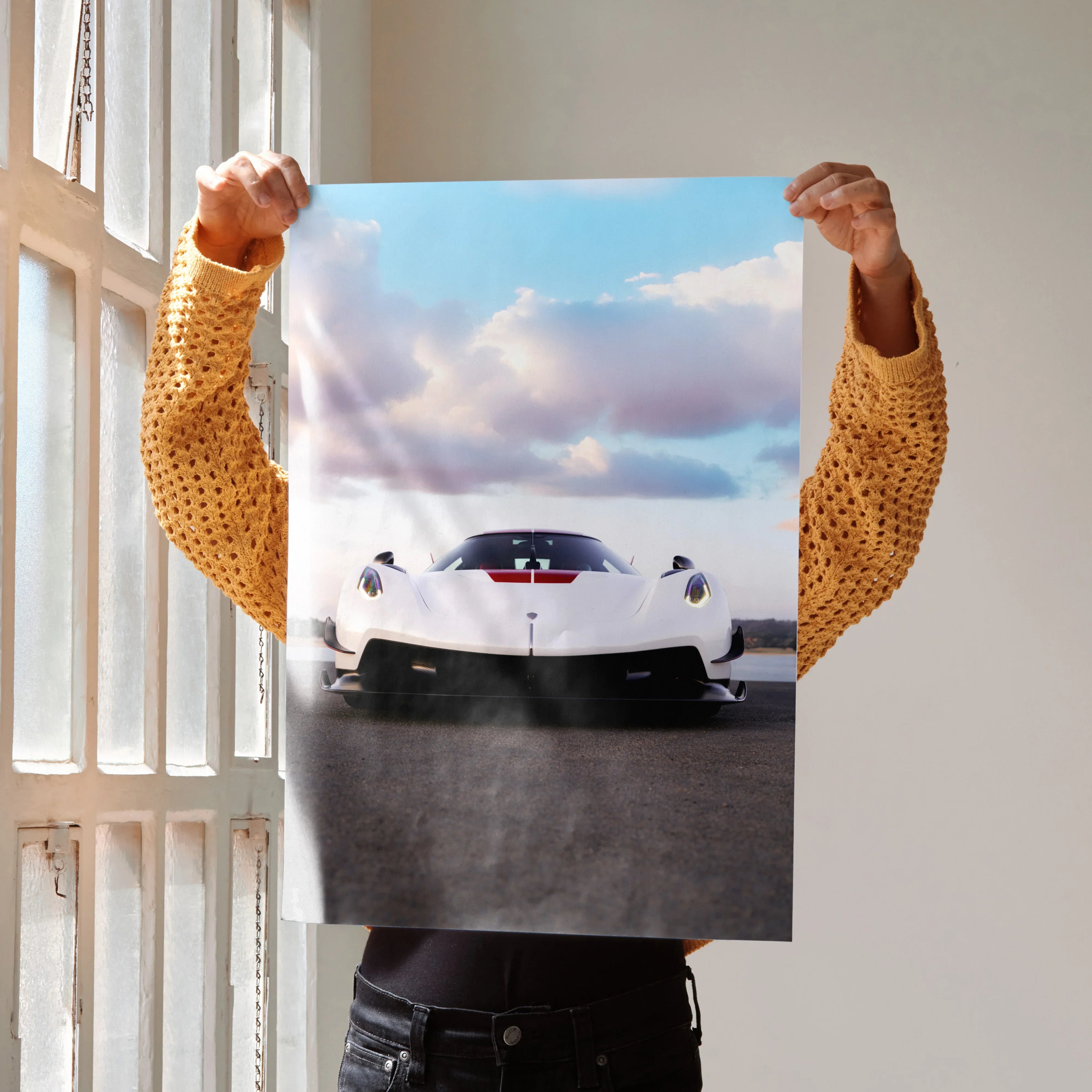 Koenigsegg Jesko sports car poster held up with dramatic sky background, wall art in vibrant colors.