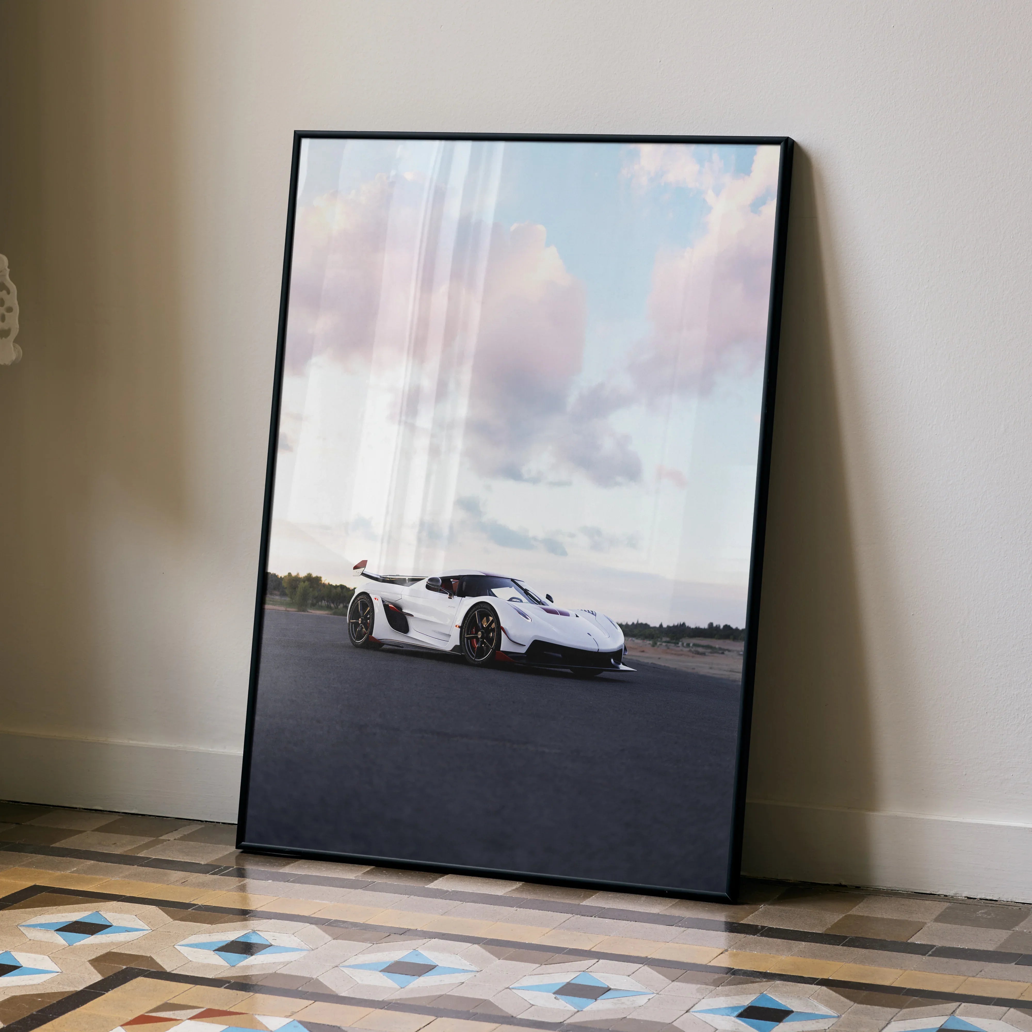 Koenigsegg Jesko white sports car poster leaning on wall with cloudy sky wall art.