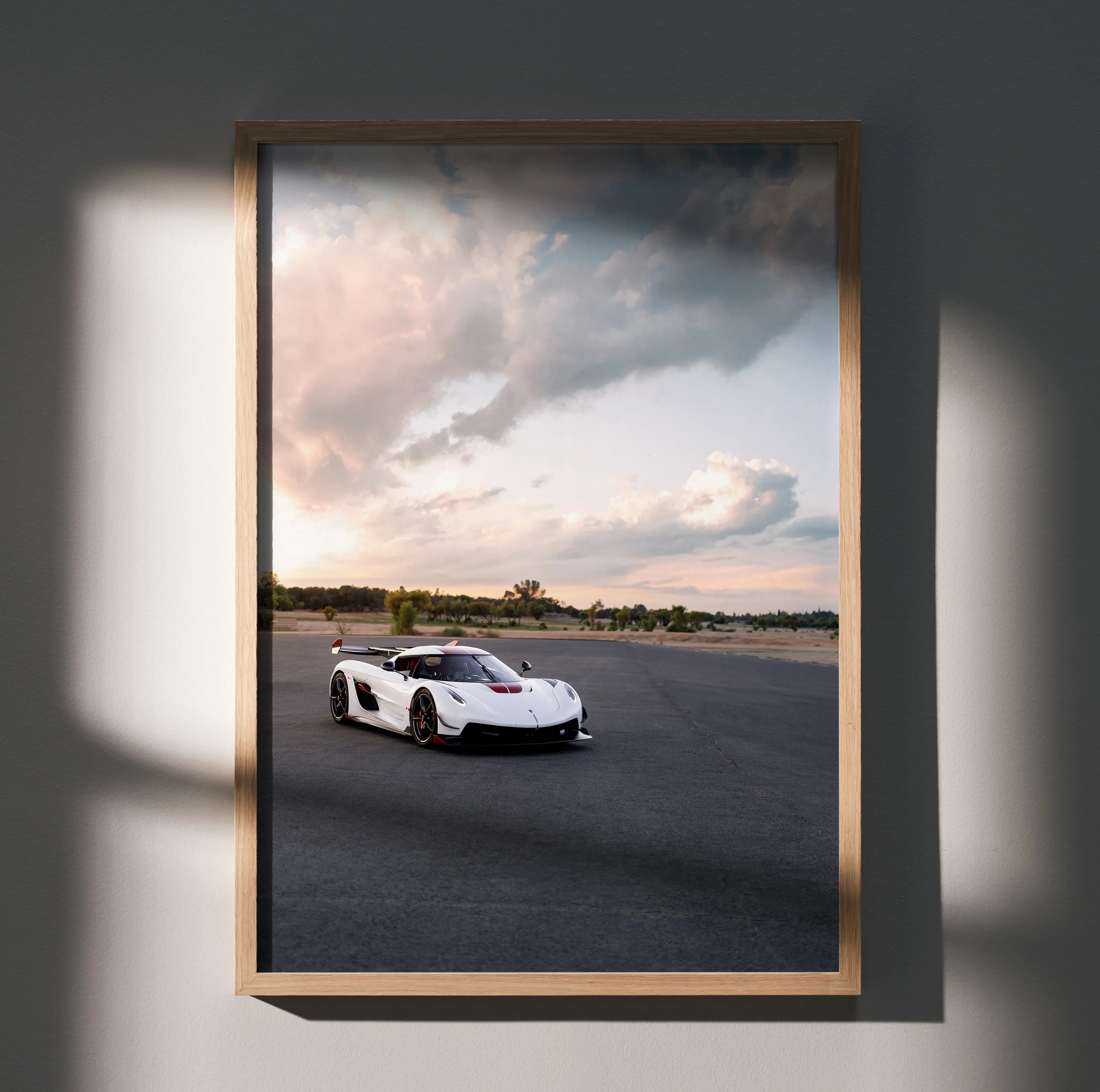 Koenigsegg Jesko supercar on racetrack poster wall art with dramatic cloudy sky in wooden frame.